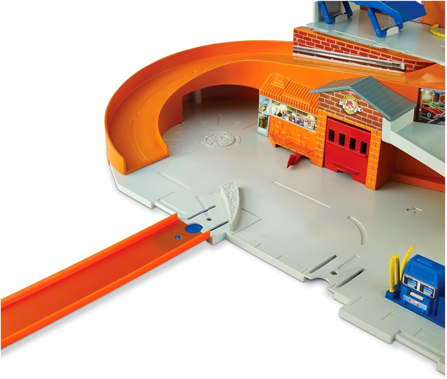 A close-up of an orange Hot Wheels track connecting to a grey base section of the Sto & Go playset, illustrating track expansion capability.
