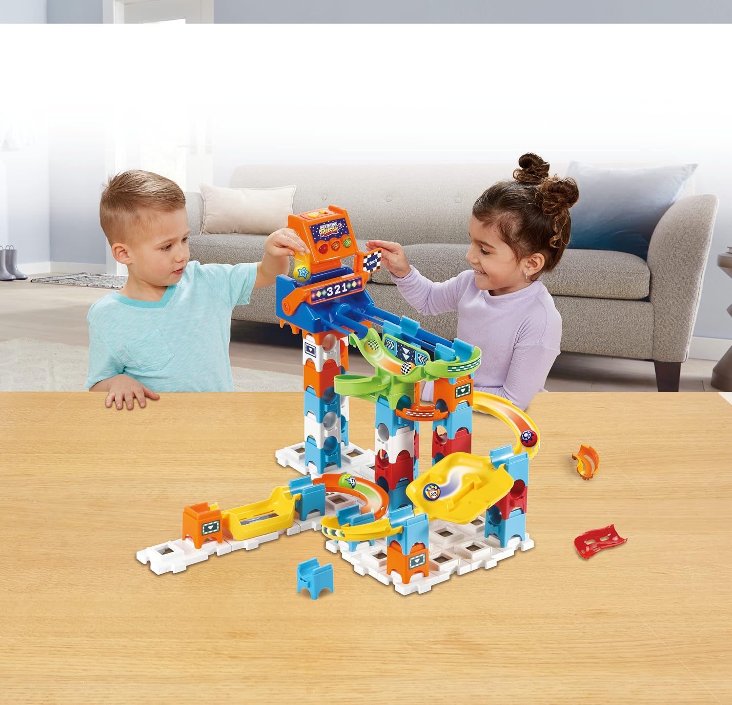 Two children playing with the VTech Marble Rush Speedway on a wooden table.