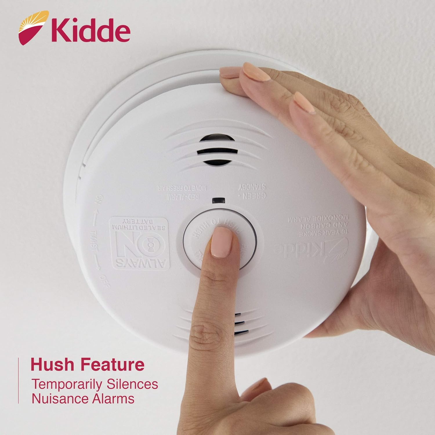 A finger pressing the 'Push to Test/Hush' button on the Kidde i12010SCO alarm.