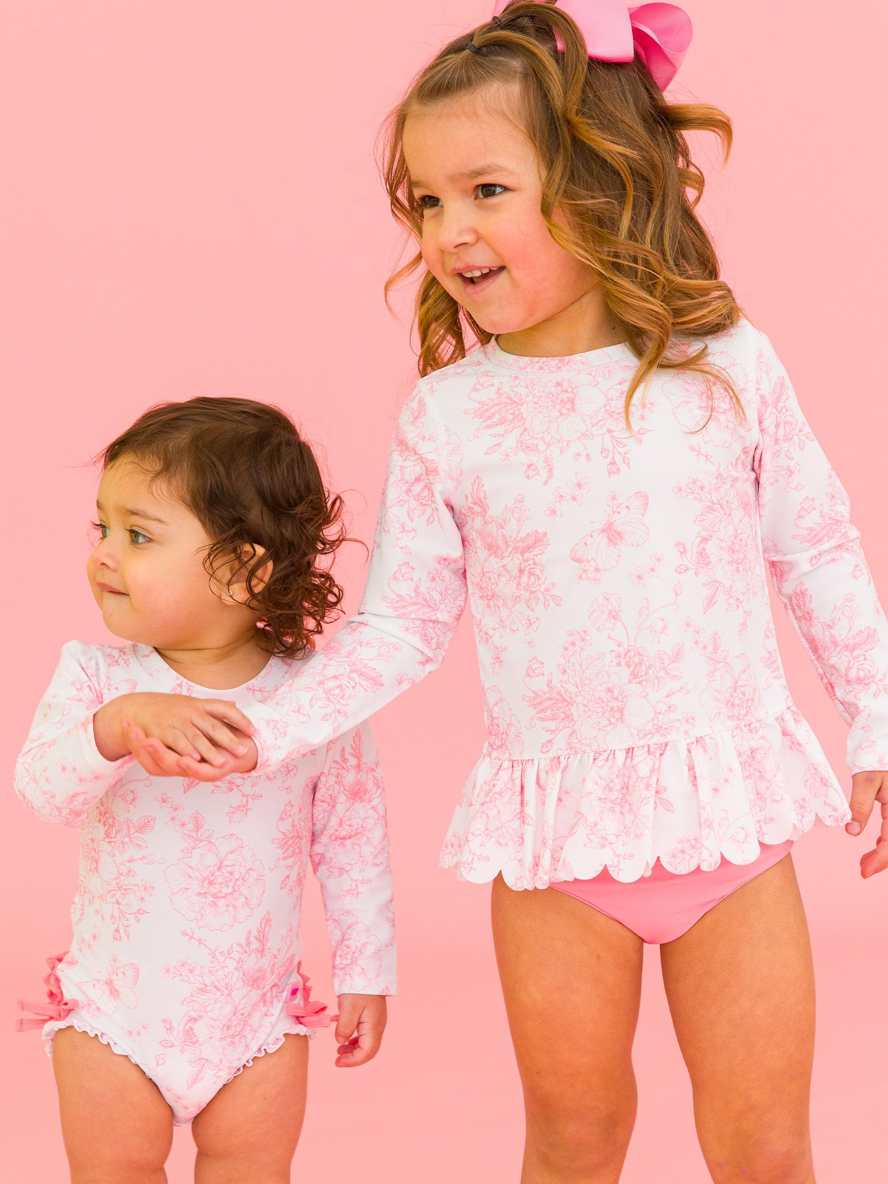RuffleButts Traje de baño de Dos Piezas Festoneado de Manga Larga con protección Solar UPF50 para niñas pequeñas - Toile de Mariposas en Rosa Chicle (12-18 Meses)