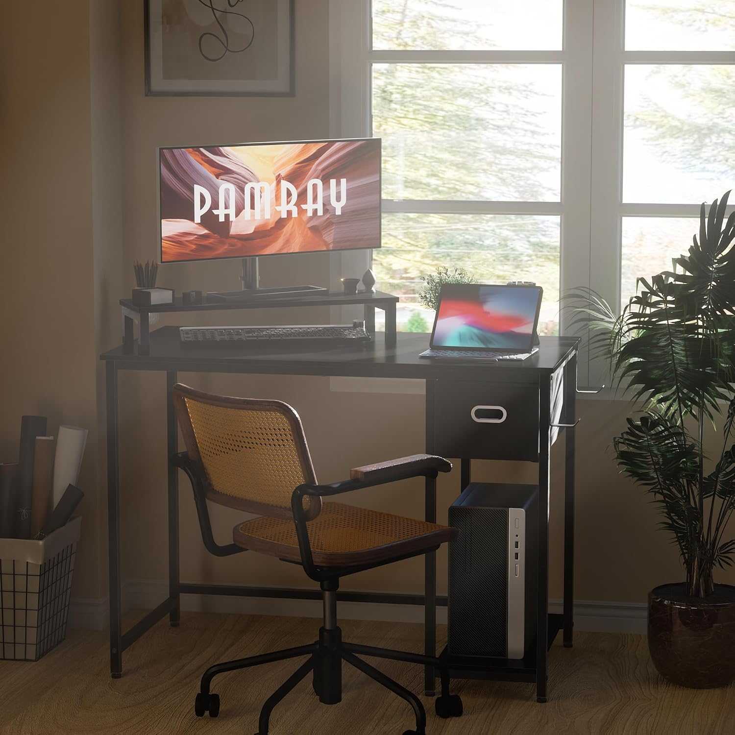 User sitting at the Pamray desk with a monitor on the stand, demonstrating ergonomic posture.