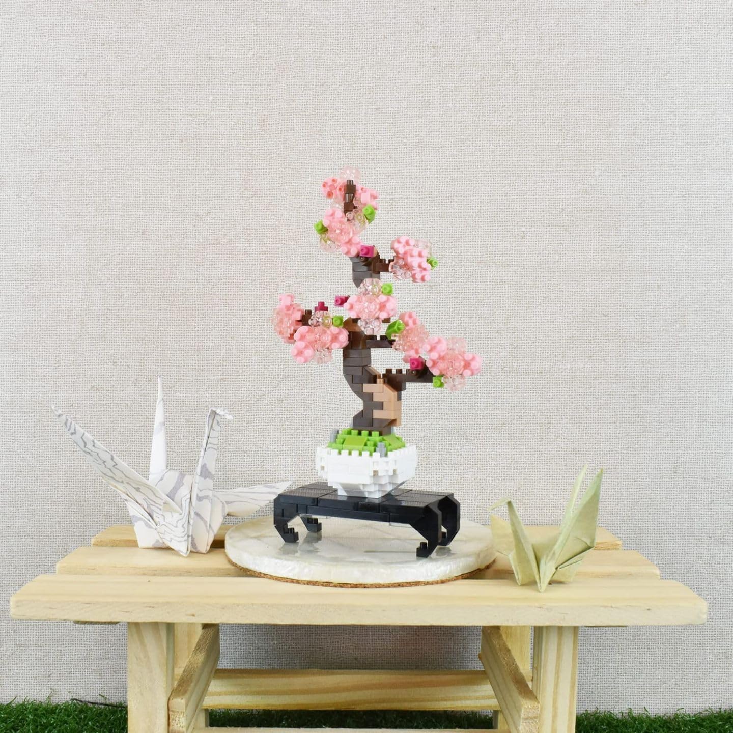 nanoblock Bonsai Sakura model displayed on a wooden table with origami cranes.