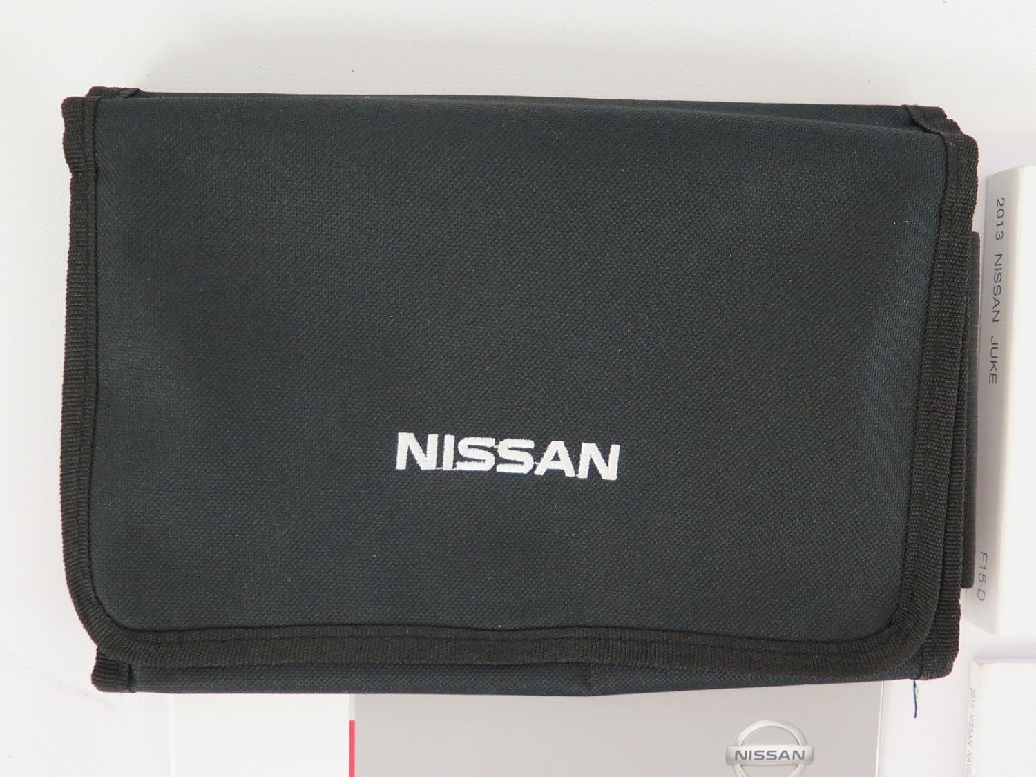 Collection of 2013 Nissan Juke manuals stored in a black fabric case