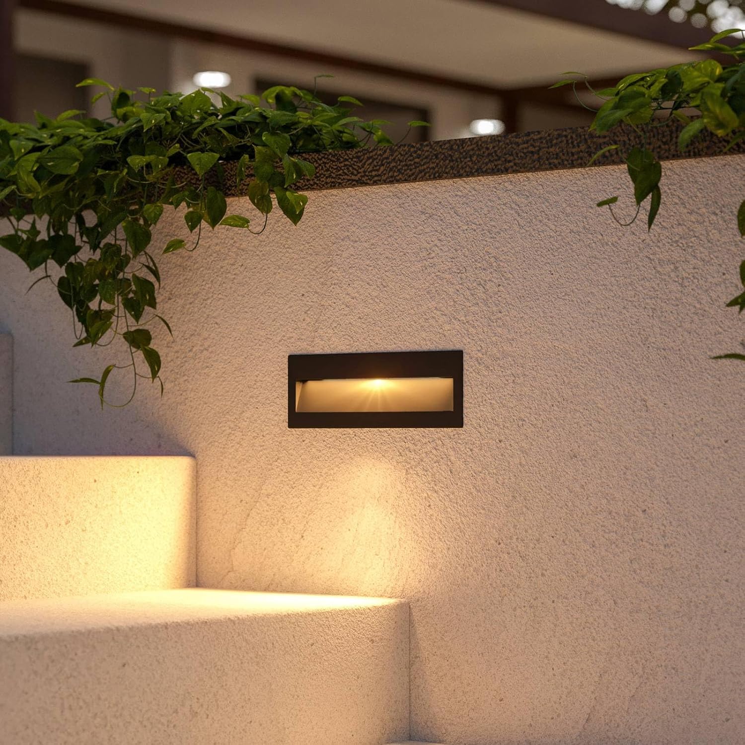 Lucande Loya LED wall light installed on an outdoor staircase, emitting a warm light downwards, illuminating the steps.