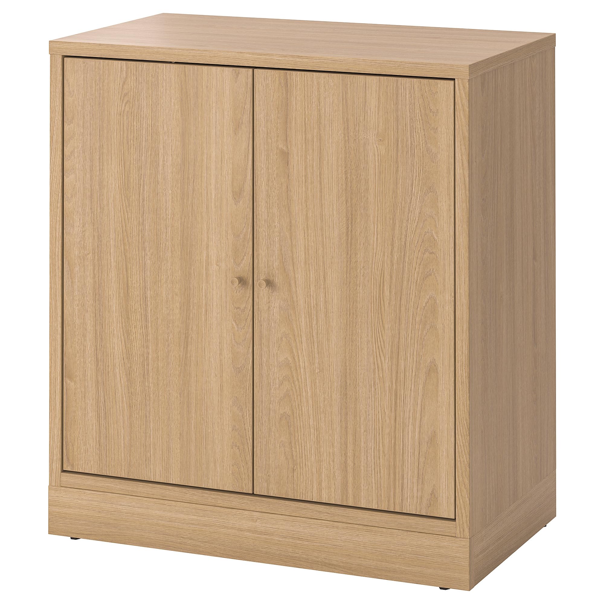 The TONSTAD cabinet with doors, made of oak veneer, positioned in a living room setting with decor on top.