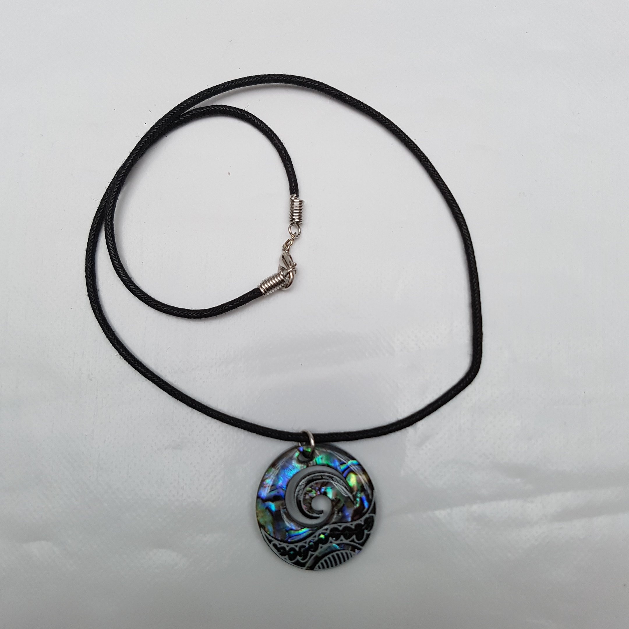 Collier à pendentif Maori Koru ou Wave Crest - Incrustation d'ormeau paua bleuté et vert sur disque en plastique noir - Avec cordon noir de 45,7 cm