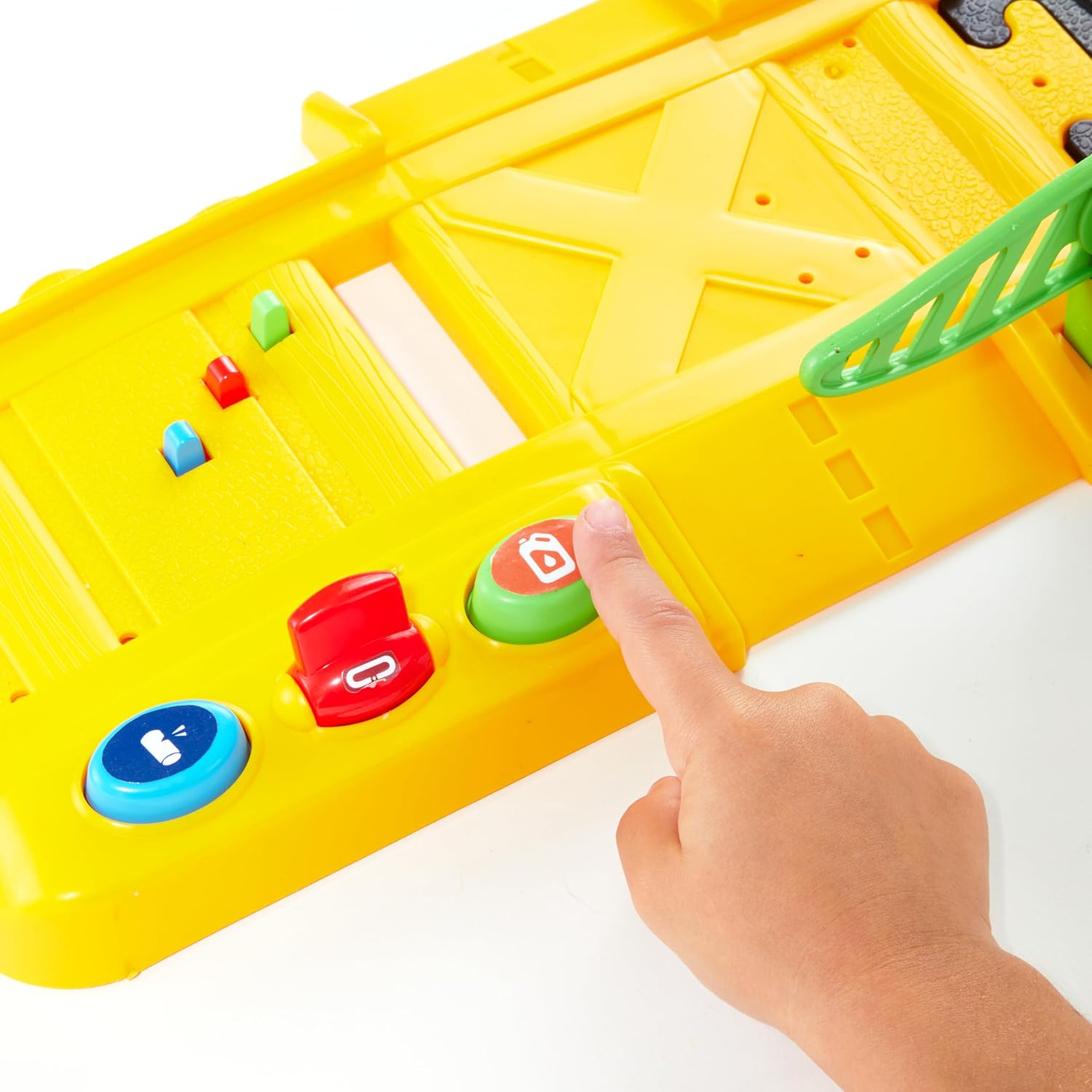 Close-up of a child's hand pressing a button on the yellow railroad crossing control station, which is integrated into the train track.