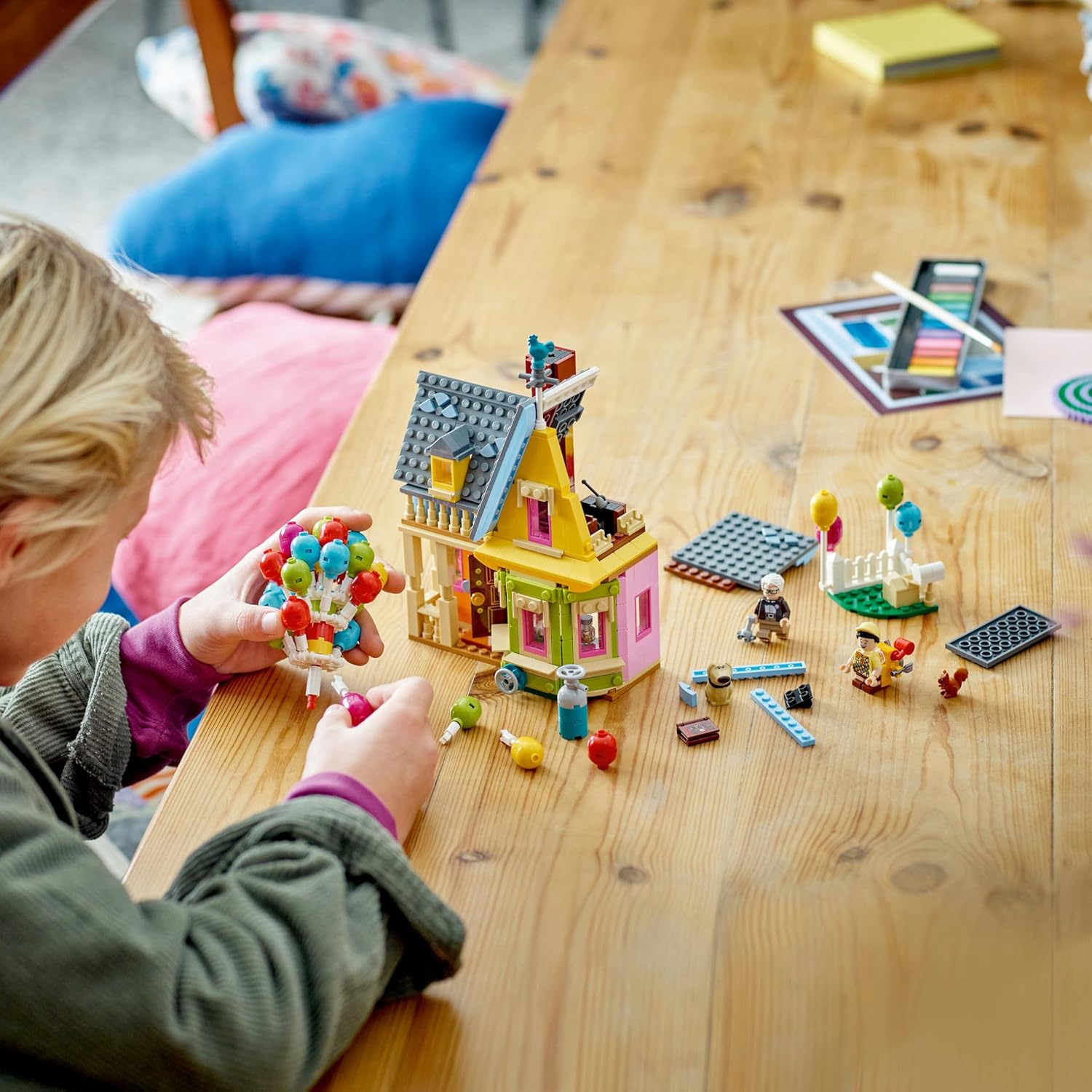 A child sorting and building with LEGO pieces for the Up House set.