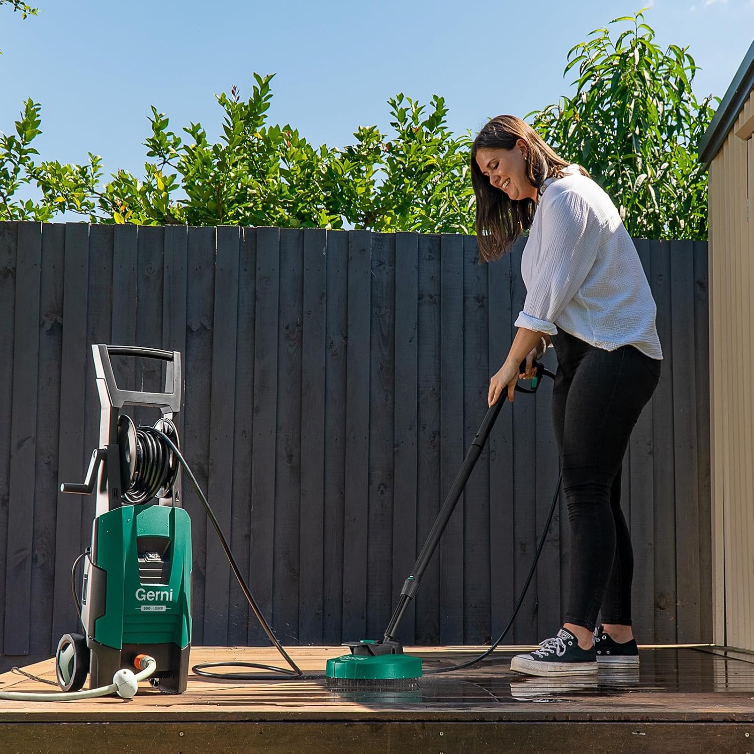 Woman using the patio cleaner attachment on a wooden deck