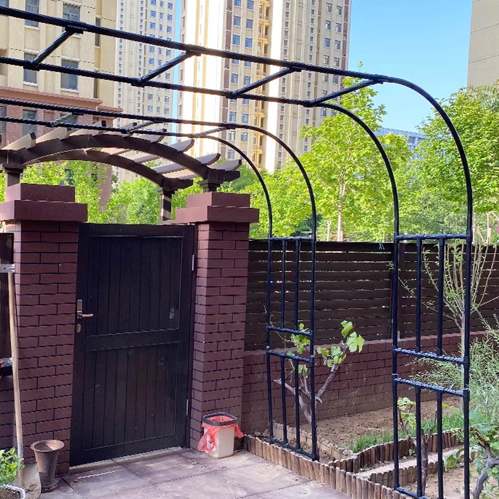 Pergola murale noire pour ombrager une terrasse avec des rosiers