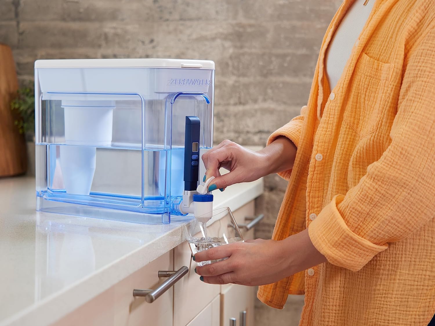 Woman dispensing filtered water from the ZeroWater dispenser into a glass