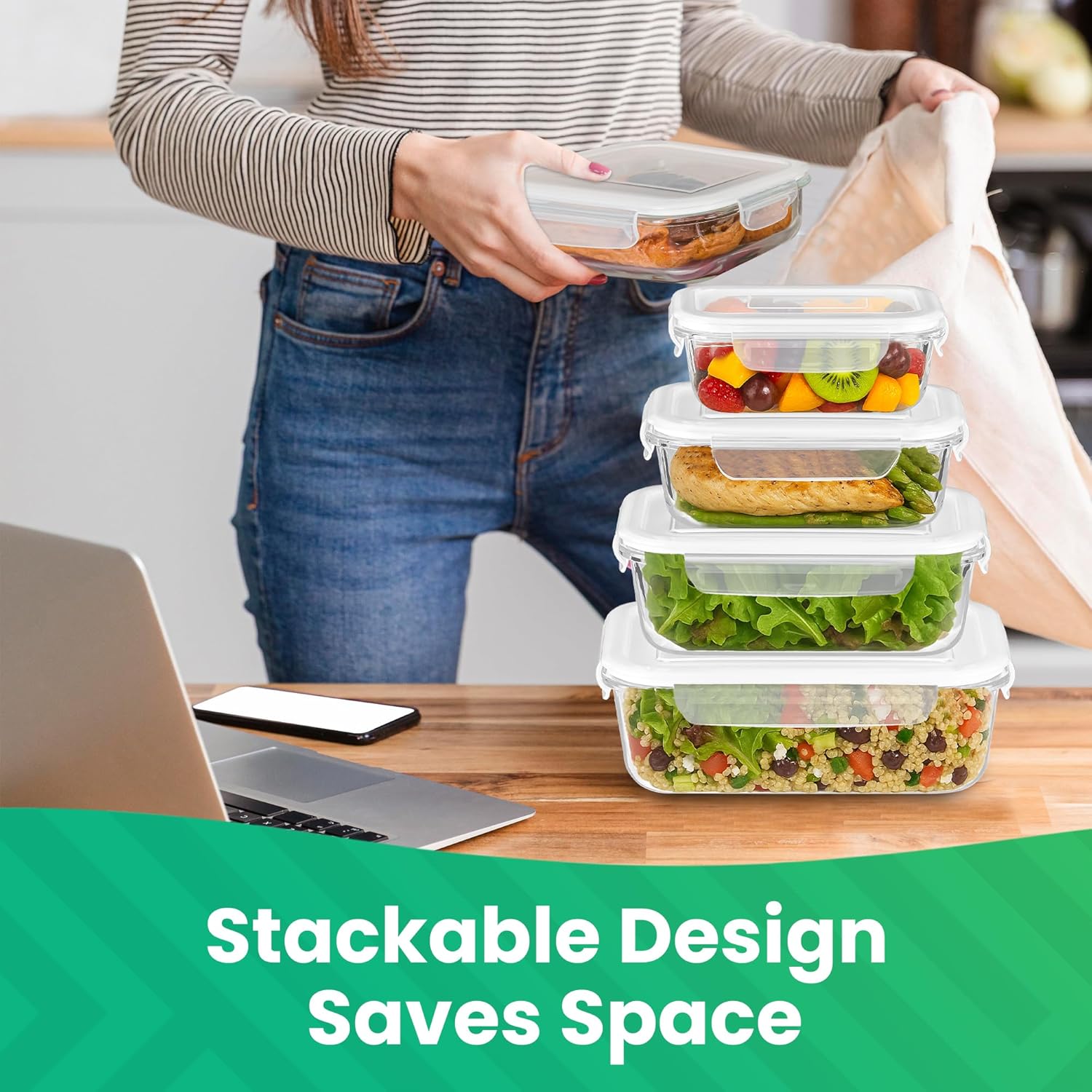 A person stacking Innoteck Essentials glass food containers on a kitchen counter next to a laptop, demonstrating their space-saving design.
