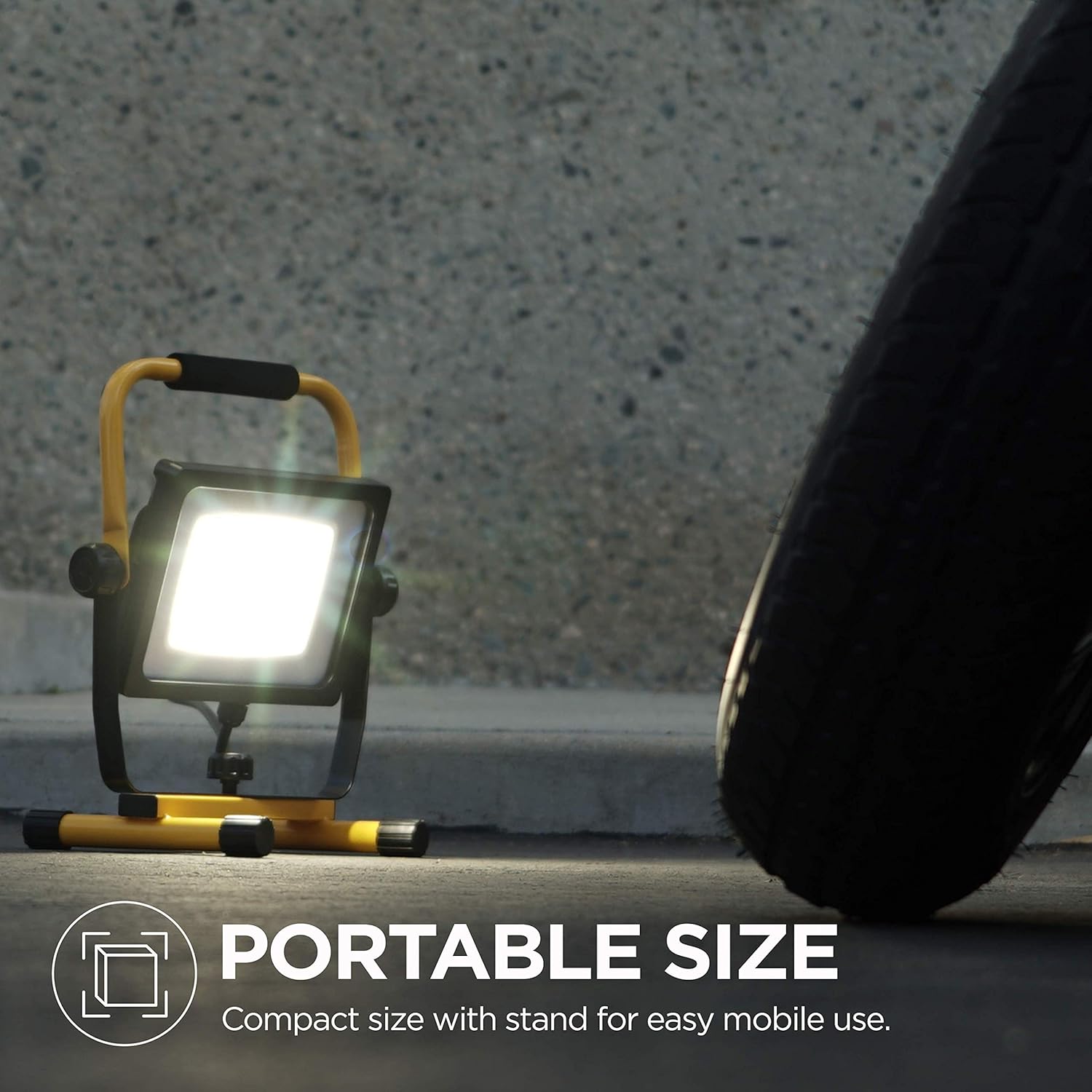 Home Zone LED Work Light, portable size, next to a tire