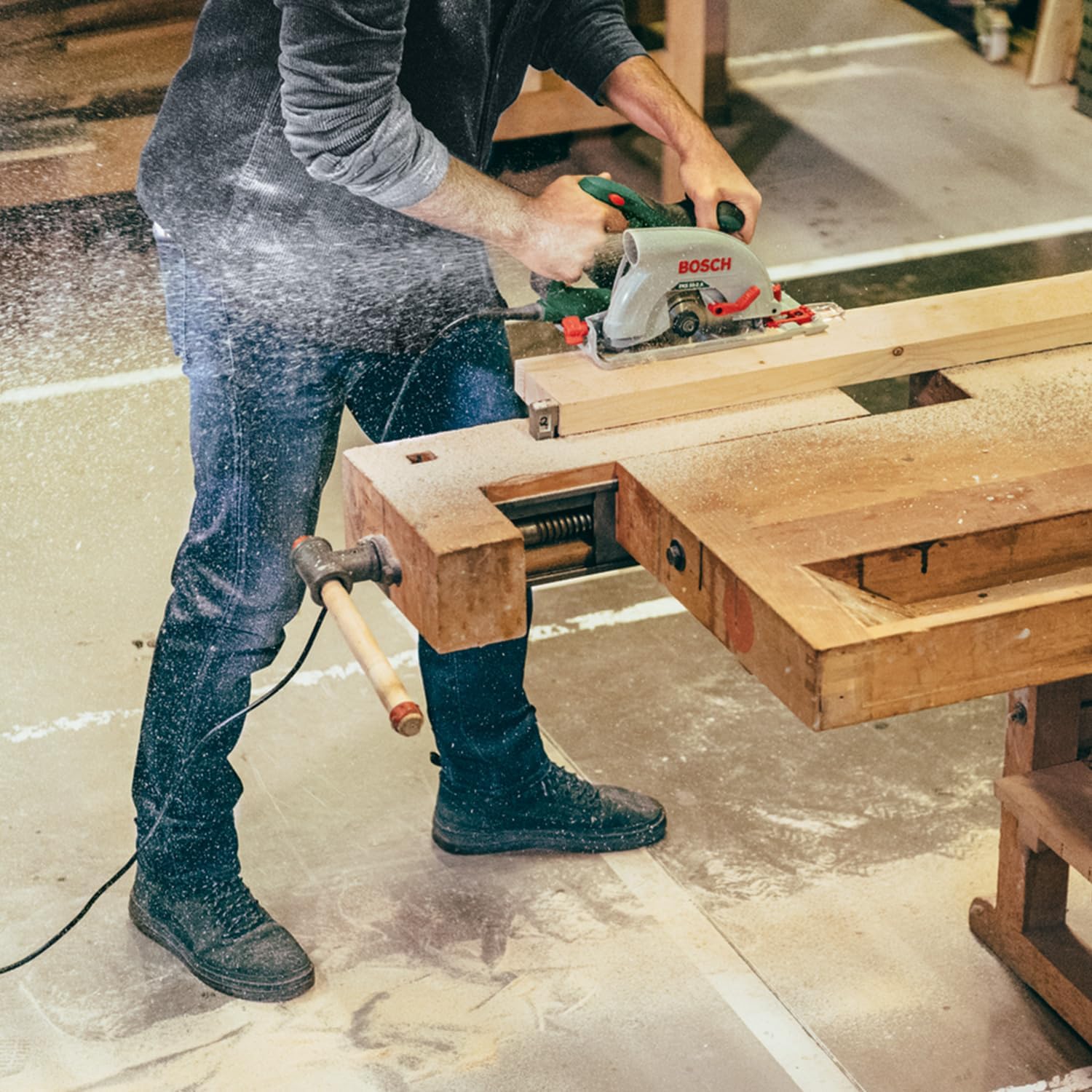 User operating Bosch PKS 66 AF Circular Saw, cutting a larger piece of wood, with sawdust visible
