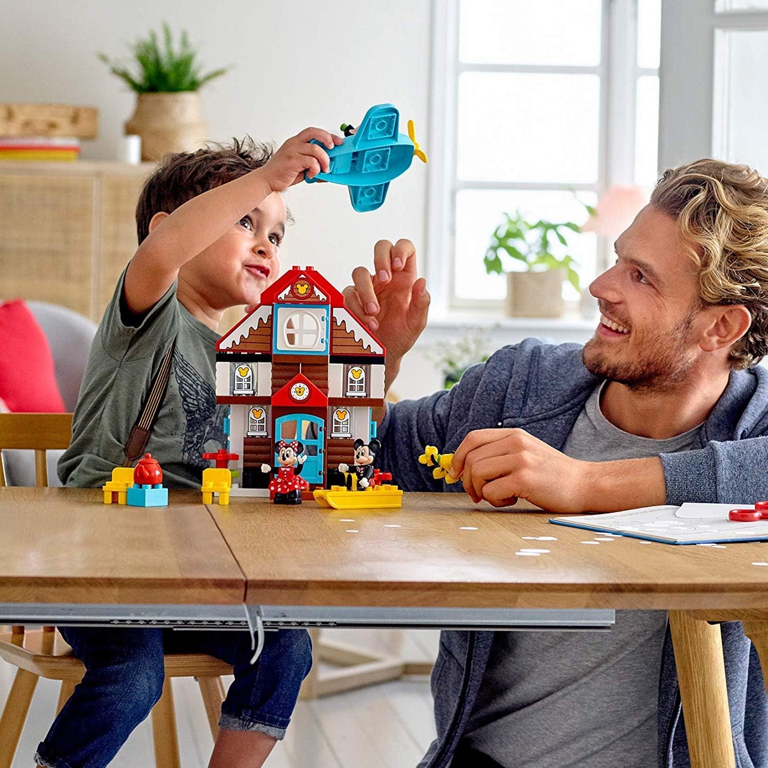 Child and adult playing with LEGO Duplo Mickey's Vacation House and Goofy's airplane