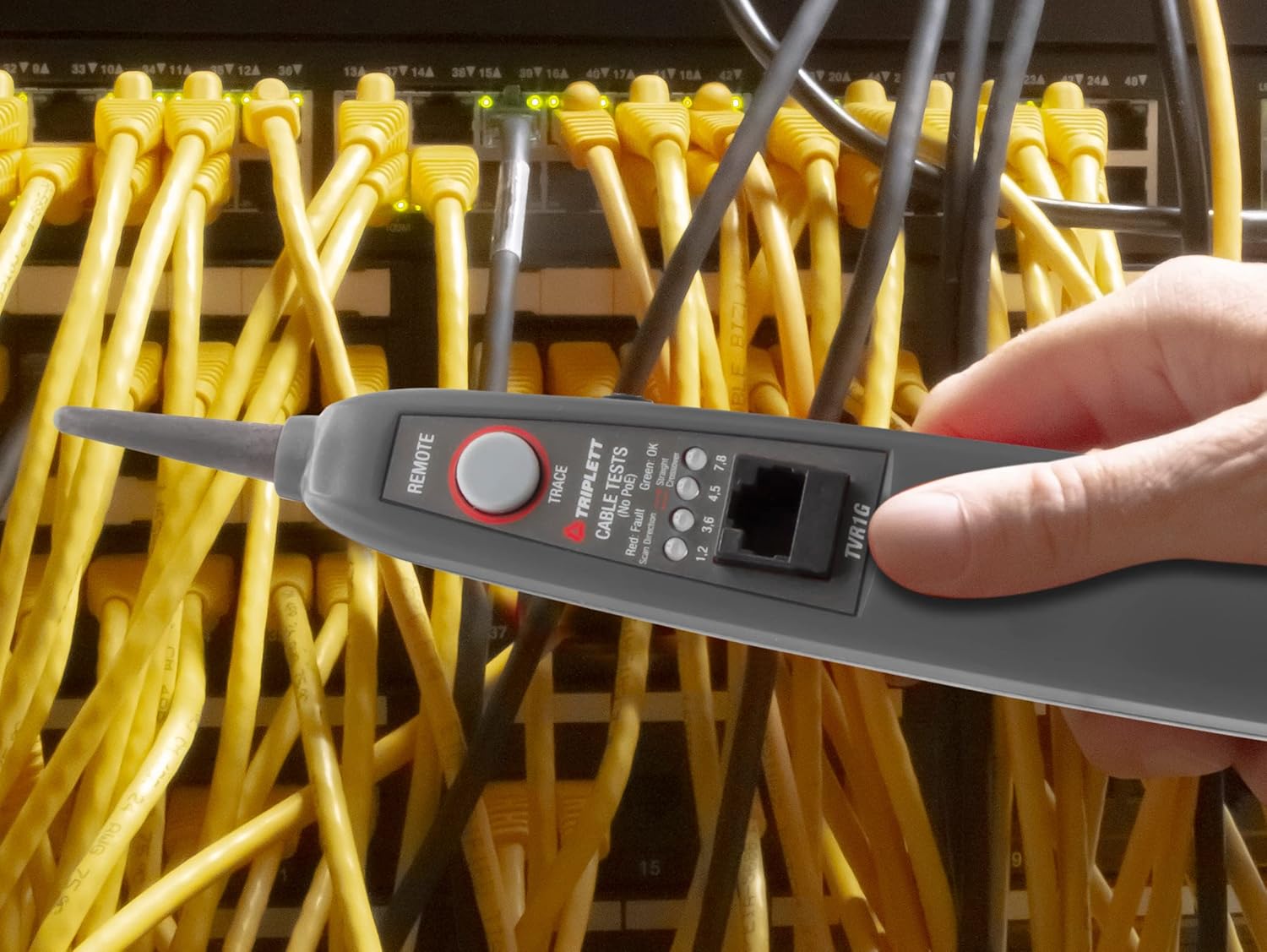 A person holding the Triplett TVR1G LAN Network Tester connected inline between network devices in a server rack.