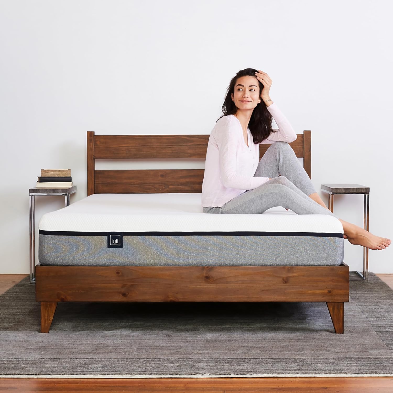Woman sitting comfortably on a Lull mattress on a wooden bed frame