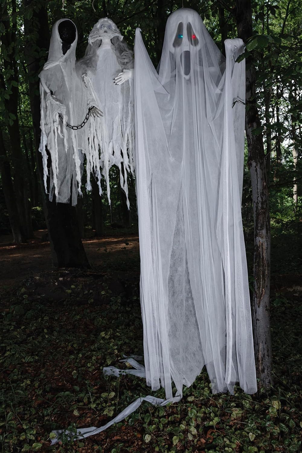 Two Boland ghost decorations, including the Faceless Ghost, hanging outdoors among trees, creating a spooky atmosphere.