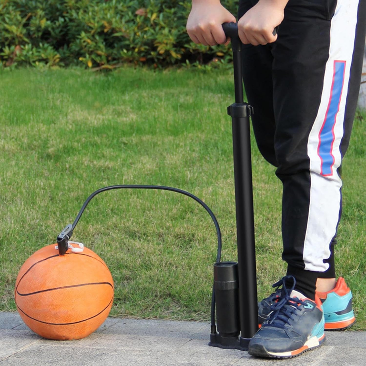 Person using the portable air pump to inflate a basketball.