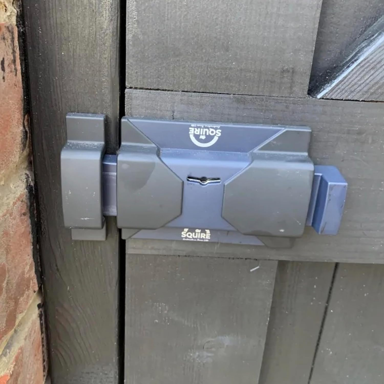 Squire Keybolt installed on a dark-colored wooden door or gate, showing a secure closure.