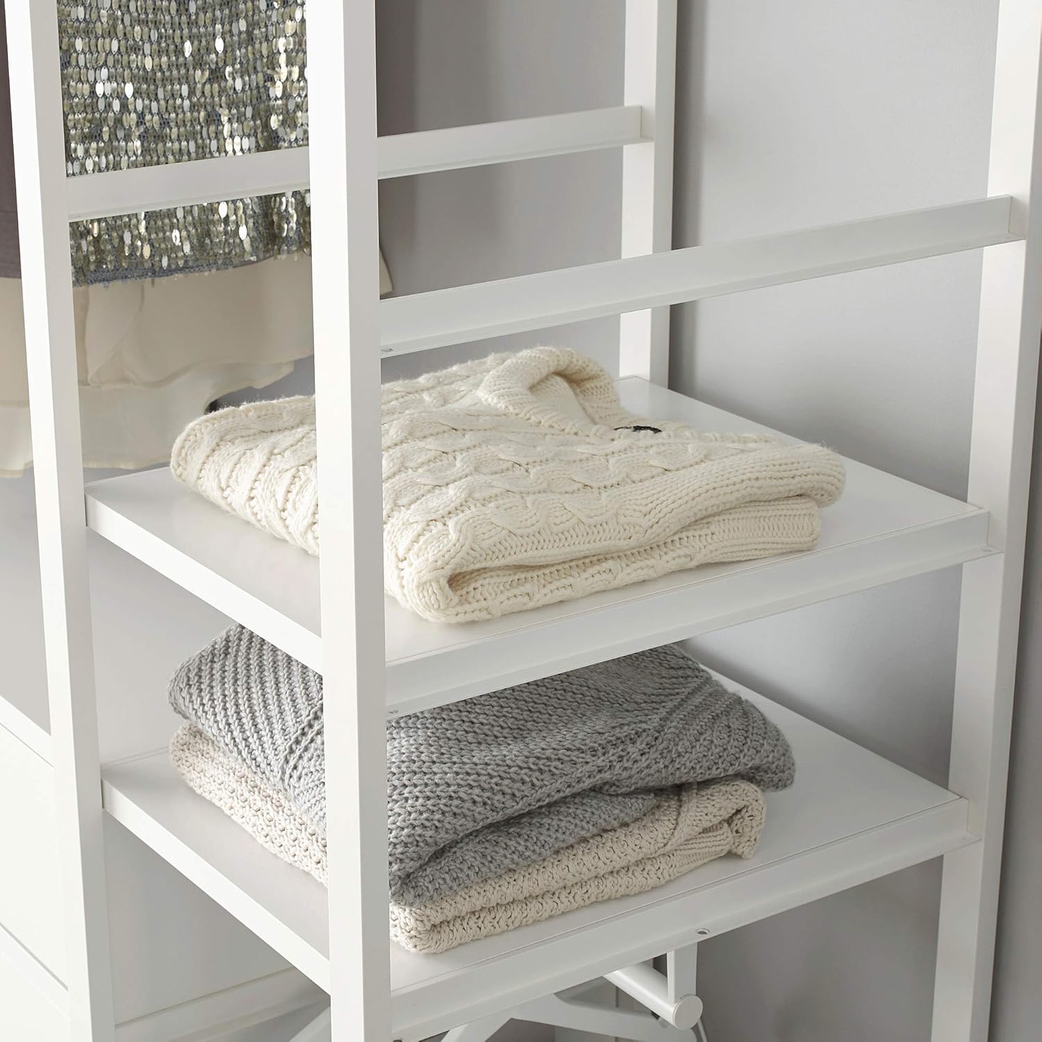 Close-up view of the ELVARLI side unit's shelves, displaying neatly folded sweaters and other textile items.