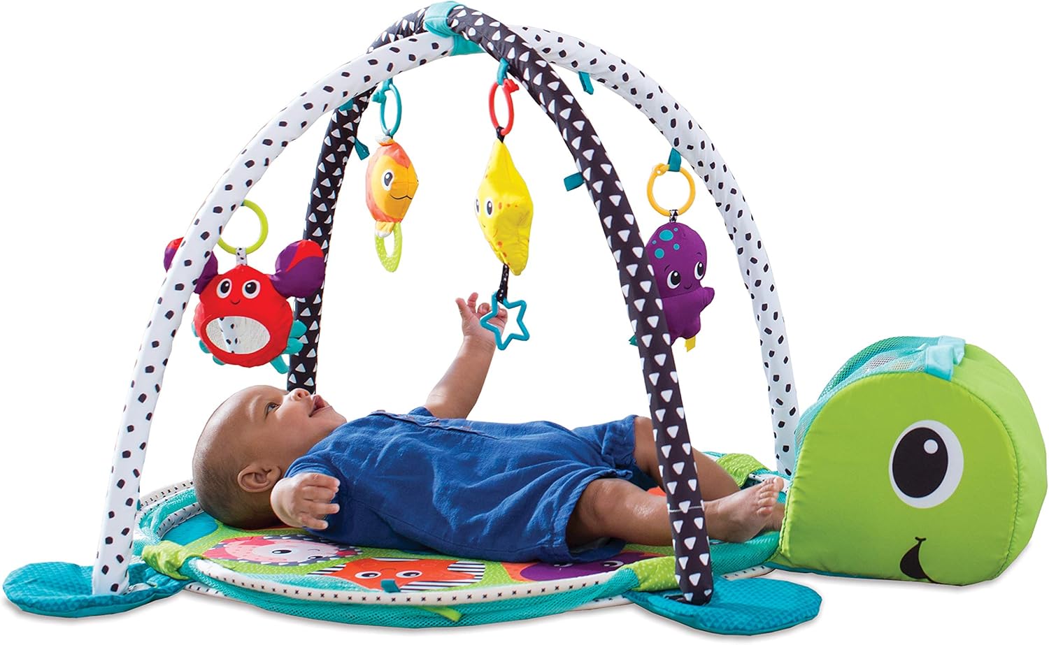 Baby lying on the Infantino Grow-with-Me Activity Gym, reaching for hanging toys.