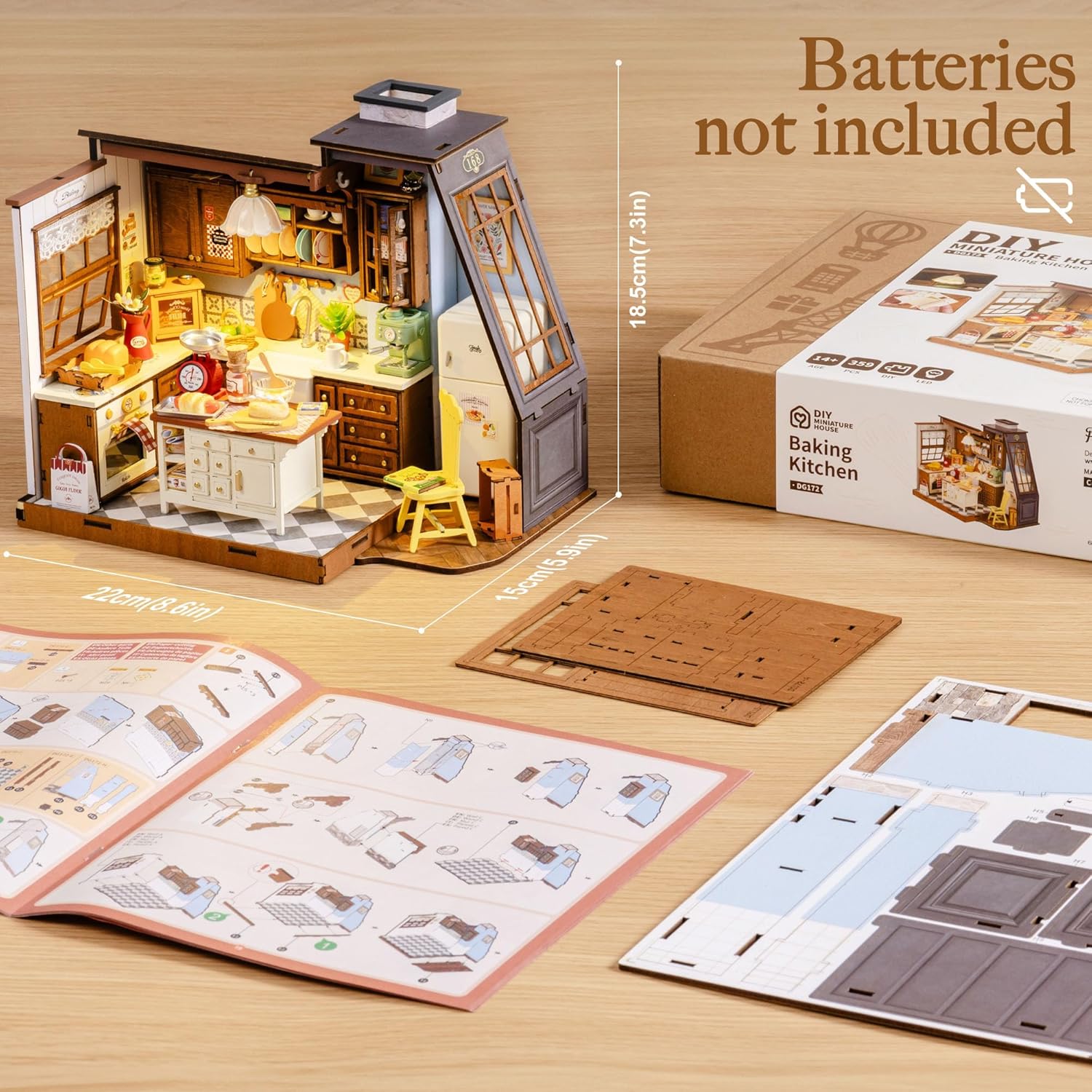 The Rolife Miniature Baking Kitchen kit next to its packaging, showing dimensions of 22cm (8.6in) width, 15cm (5.9in) depth, and 18.5cm (7.3in) height. A note indicates 'Batteries not included'.