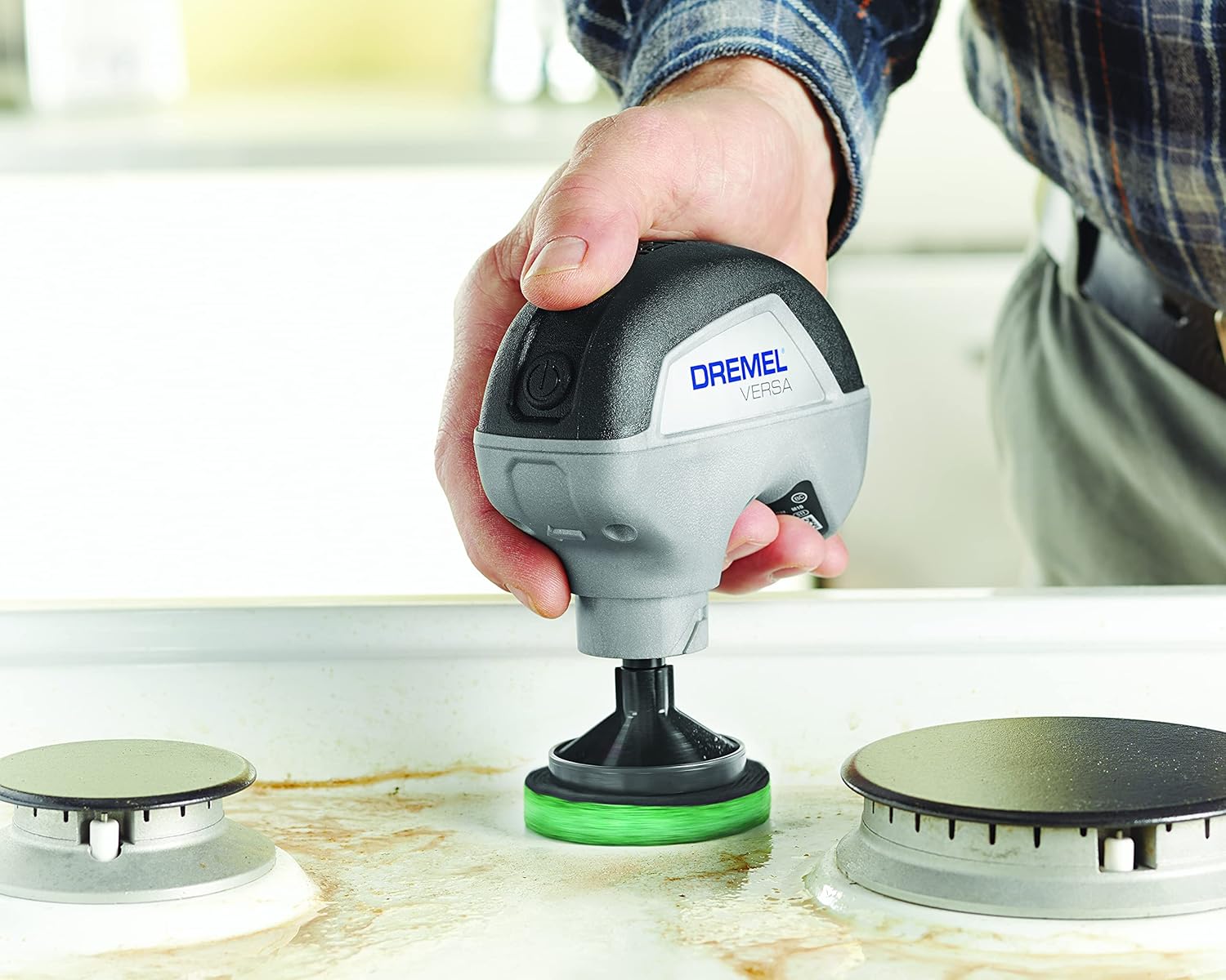 Dremel Versa cleaning a stovetop with a green kitchen scour pad