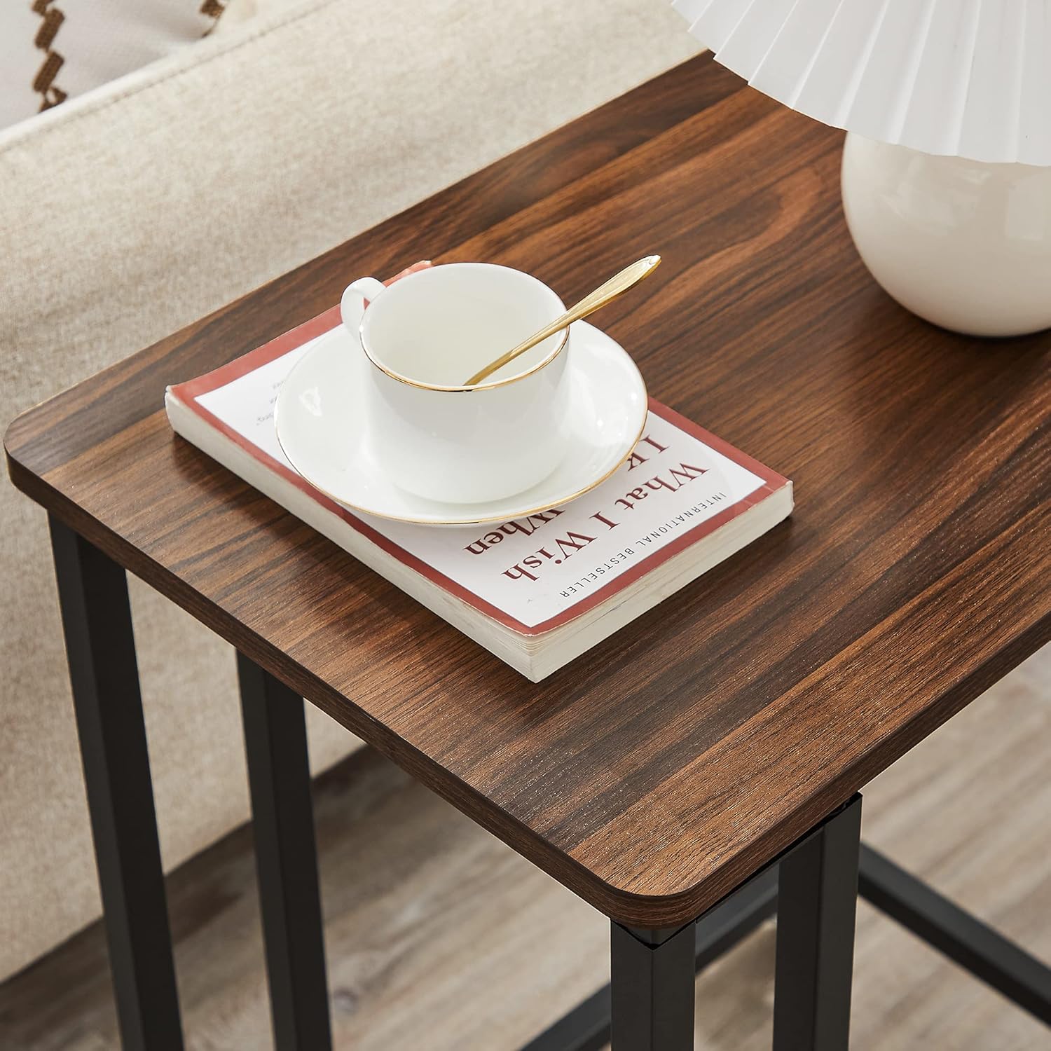 Close-up of the dark walnut tabletop with a white cup and a book