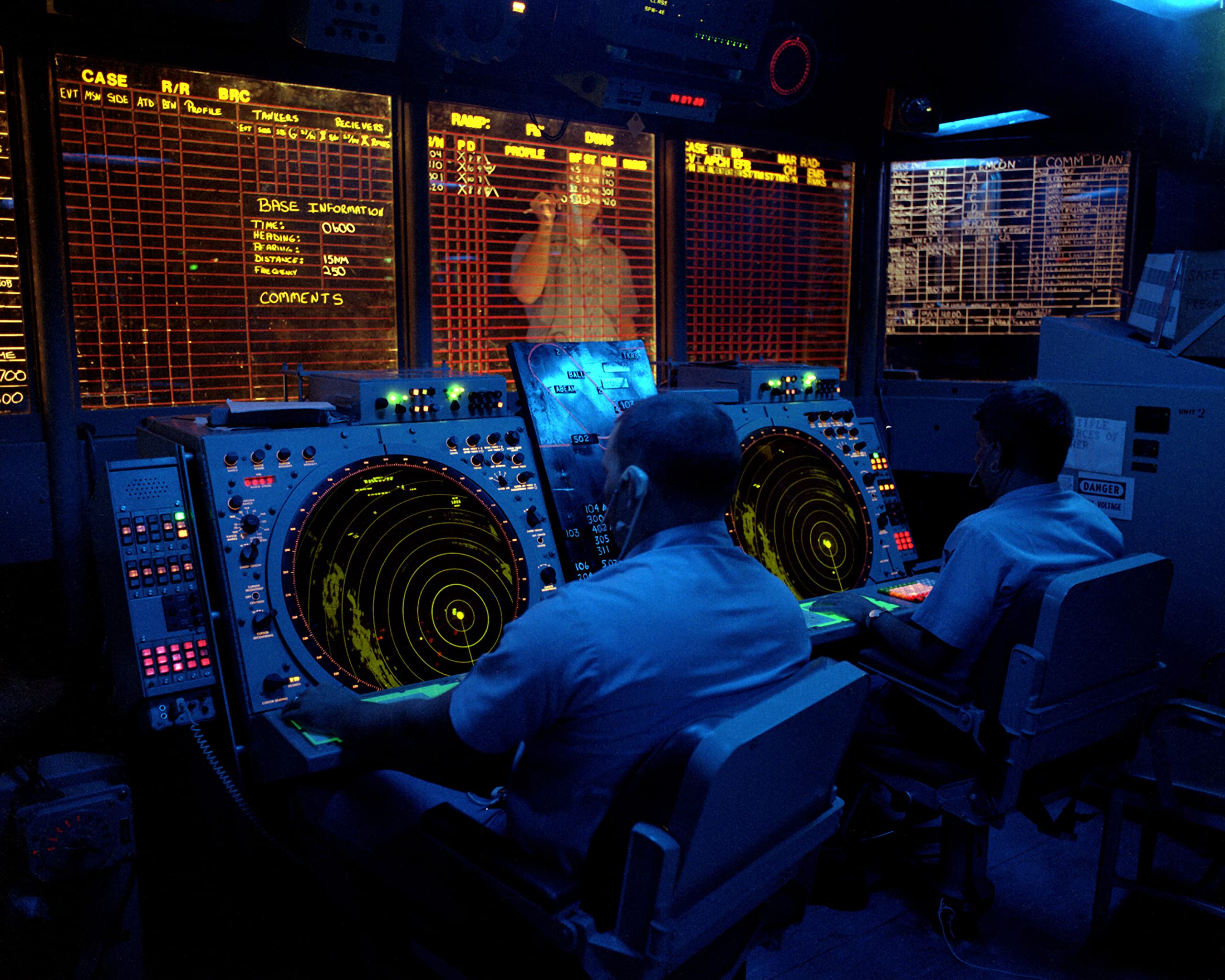 Crew members use radar screens to monitor air operations from the combat information center to the aircraft carrier USS KITTY HAWK (CV-63) - 12 Inch by 18 Inch Laminated Poster - Bright Colors And Vivid Imagery