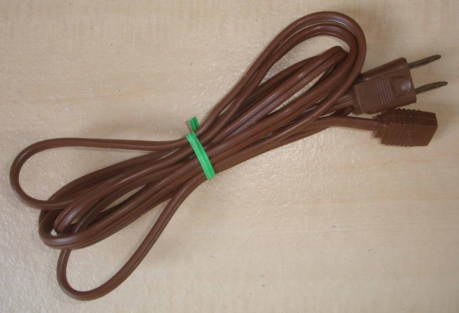Brown two-prong replacement power cord, coiled and secured with a green tie.