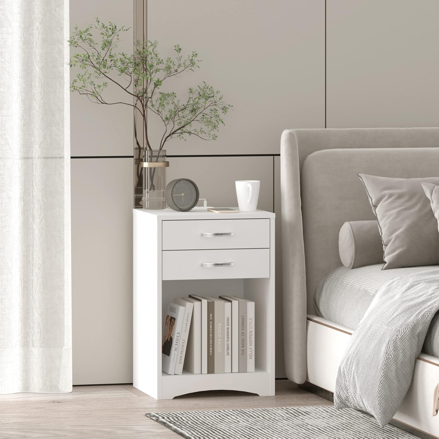 A single white nightstand next to a bed in a bedroom, with books on the shelf.