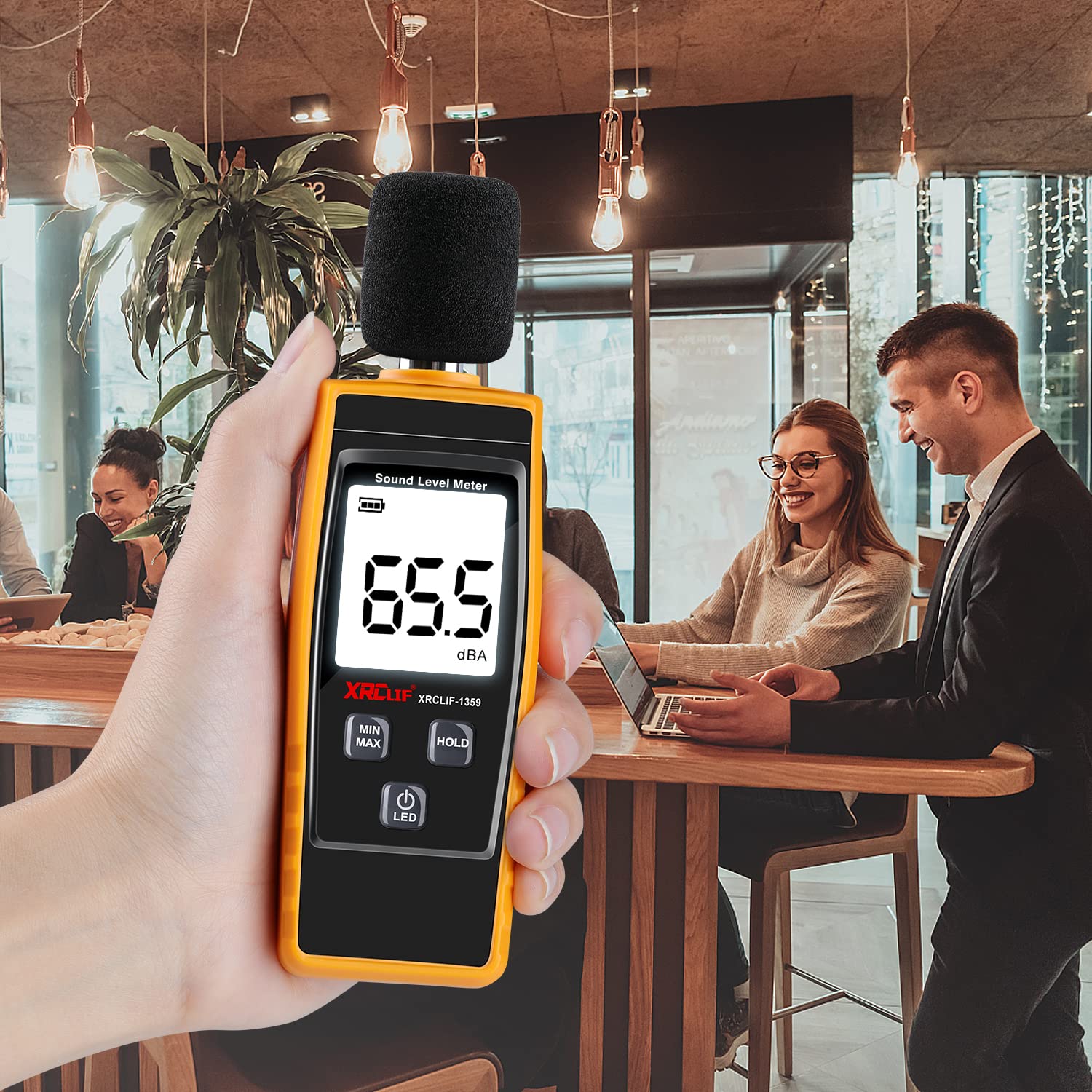 XRCLIF Decibel Meter in use in an office or cafe setting, measuring 65.5 dBA