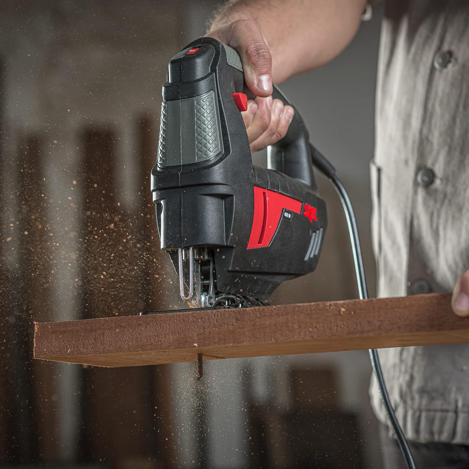 A person using the Skil 4400 Jigsaw to cut a wooden board, showing proper grip and positioning.