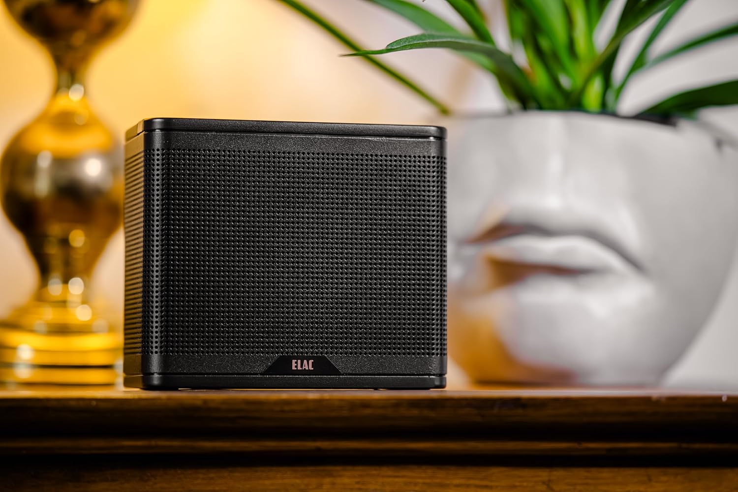 Iwaju view of the ELAC NAVA100 Portable Bluetooth Speaker in black, showcasing its perforated grille and compact design.