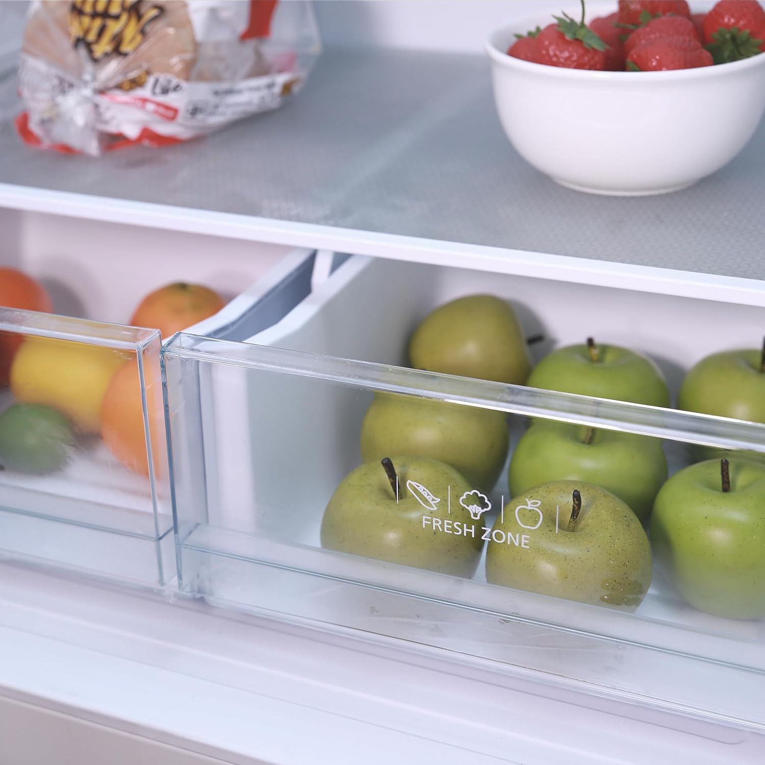 Close-up of the two clear-view crisper drawers in the refrigerator, labeled 'FRESH ZONE', containing apples and other produce.