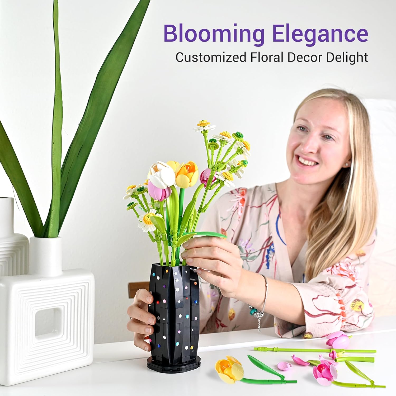 A person gently placing an artificial flower into the assembled vase, demonstrating the final steps of arranging the BAKA flower bouquet for display.