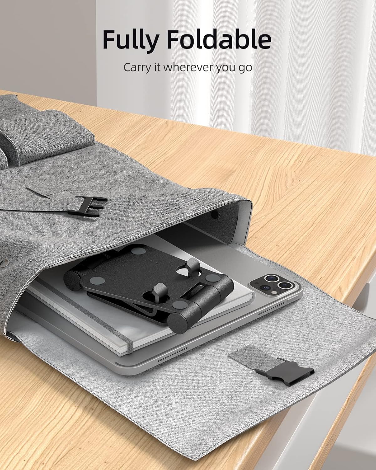 A Nulaxy phone stand folded flat and placed inside a grey bag next to a tablet, demonstrating its portability.