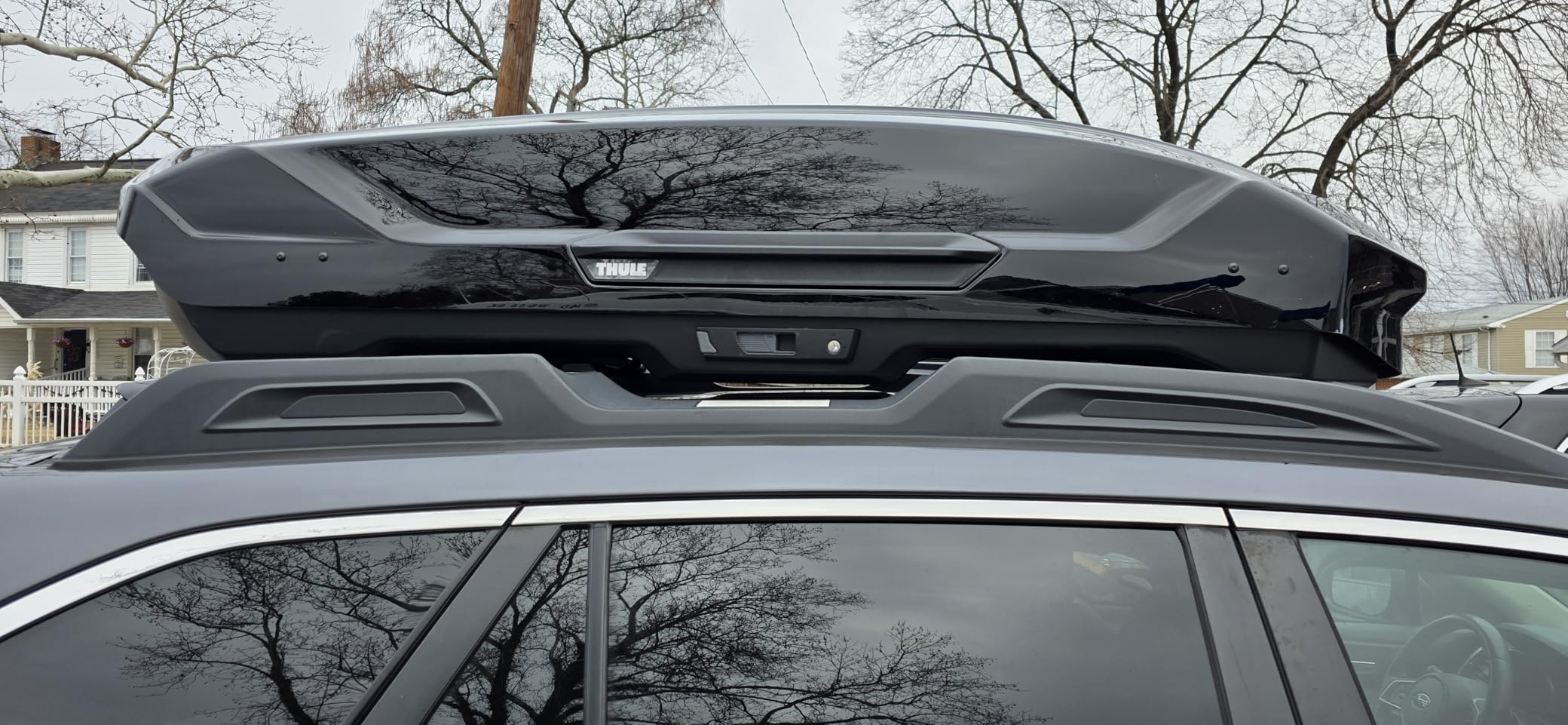 Thule Motion 3 roof cargo box mounted on black Toyota Highlander SUV in driveway
