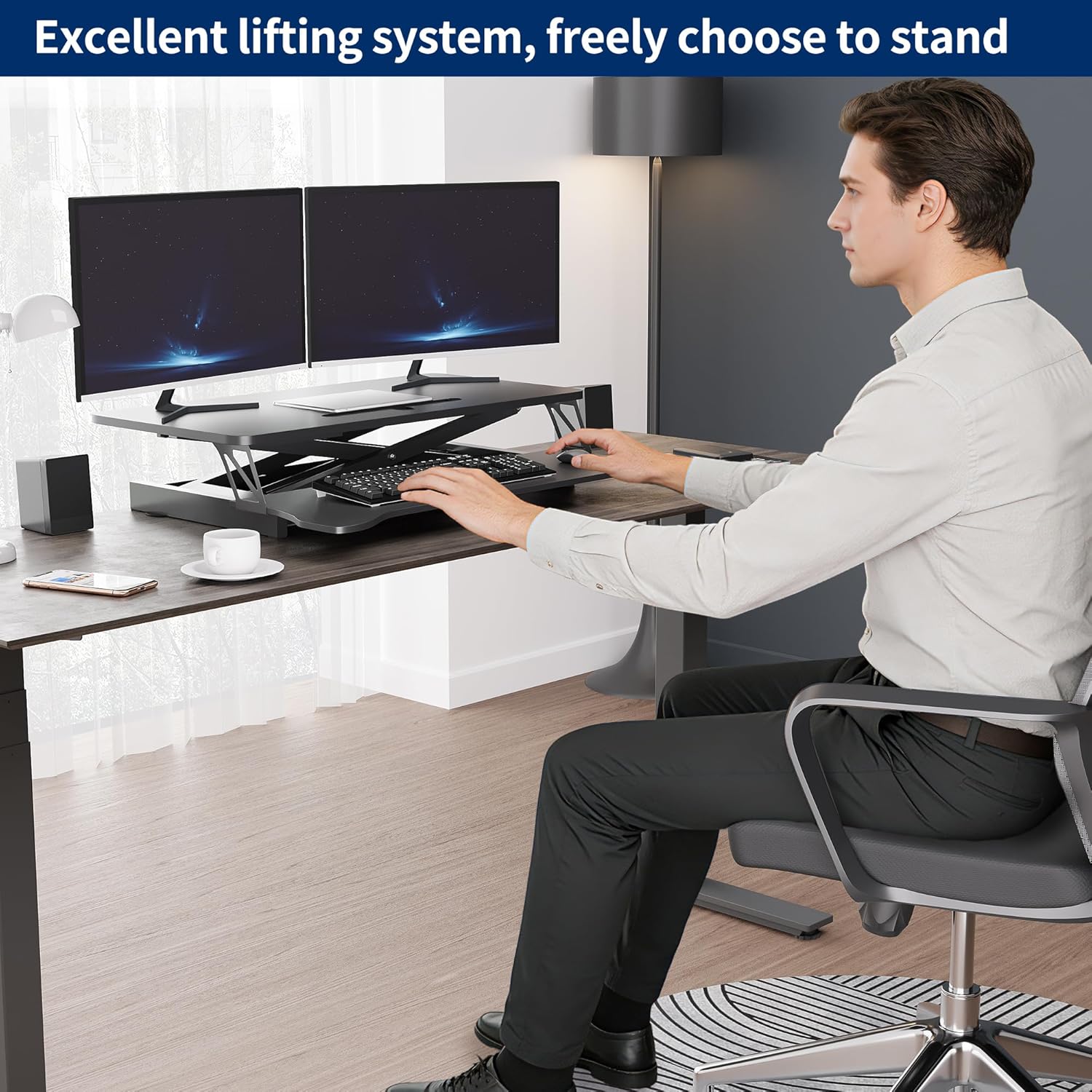 A person sitting comfortably at a desk with the Panana Standing Desk Converter in its lowest position, using a keyboard and mouse.