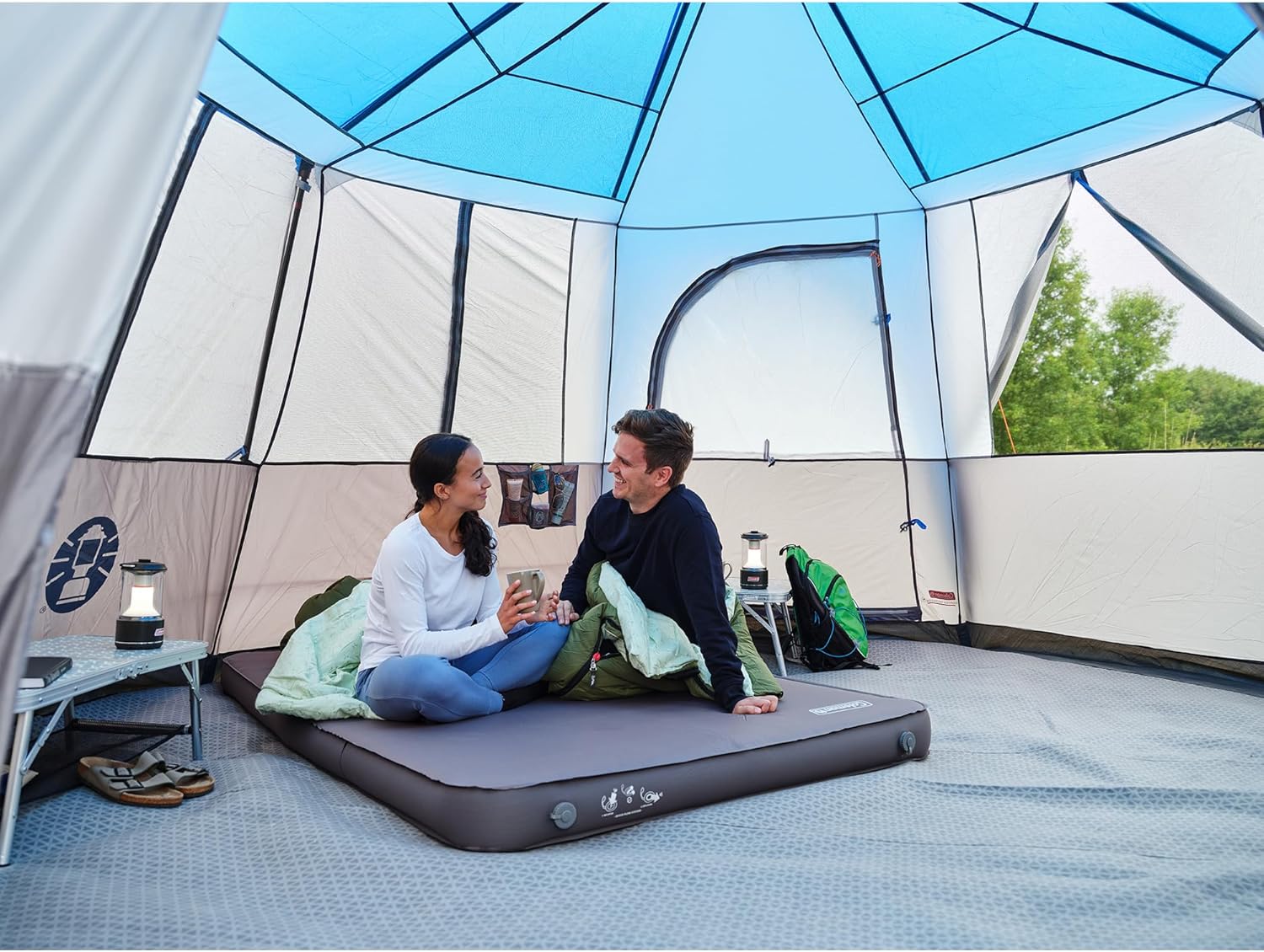 A couple sitting comfortably on the inflated mattress inside a tent