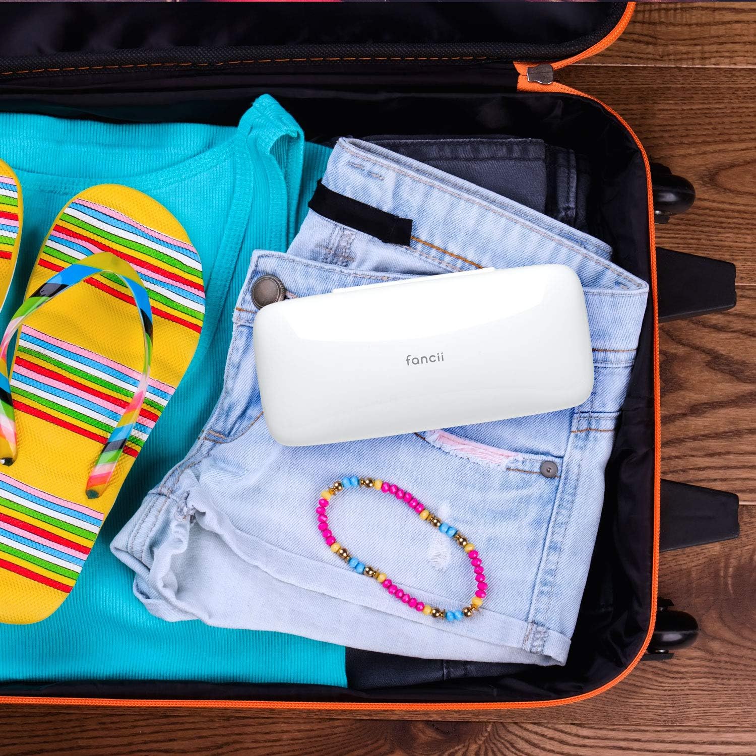 The Fancii Flawless Torri Trimmer's white travel case placed inside an open suitcase, surrounded by clothes and accessories.