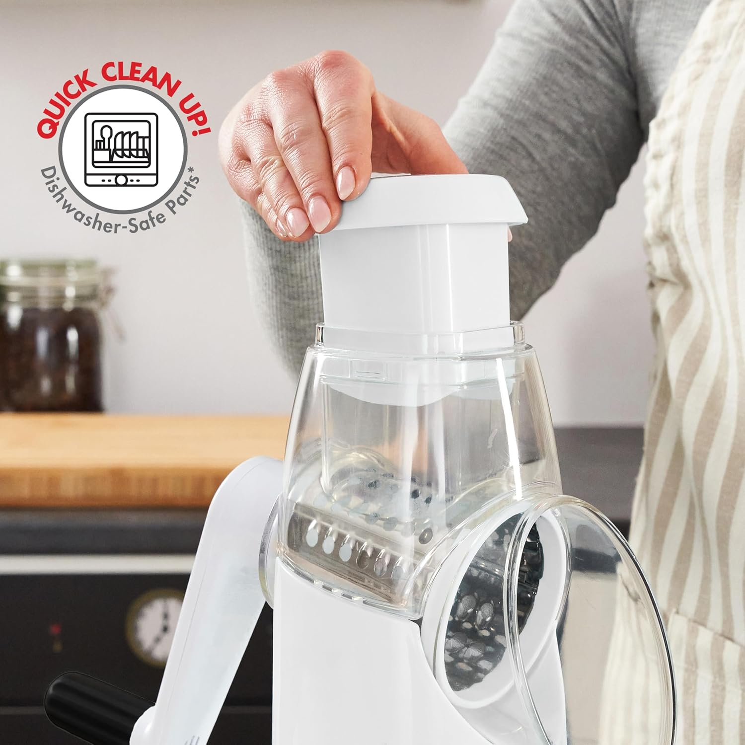 A person disassembling the Bennett Read Rota-Chef Tabletop Grater for cleaning, showing the top part being removed.