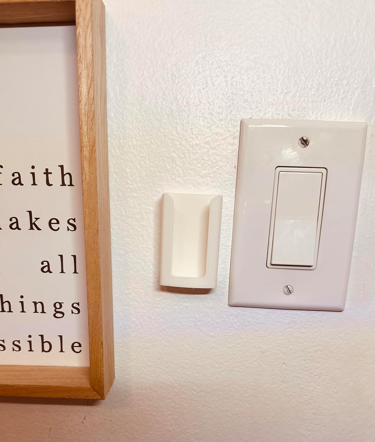 White remote holder installed on a wall next to a light switch