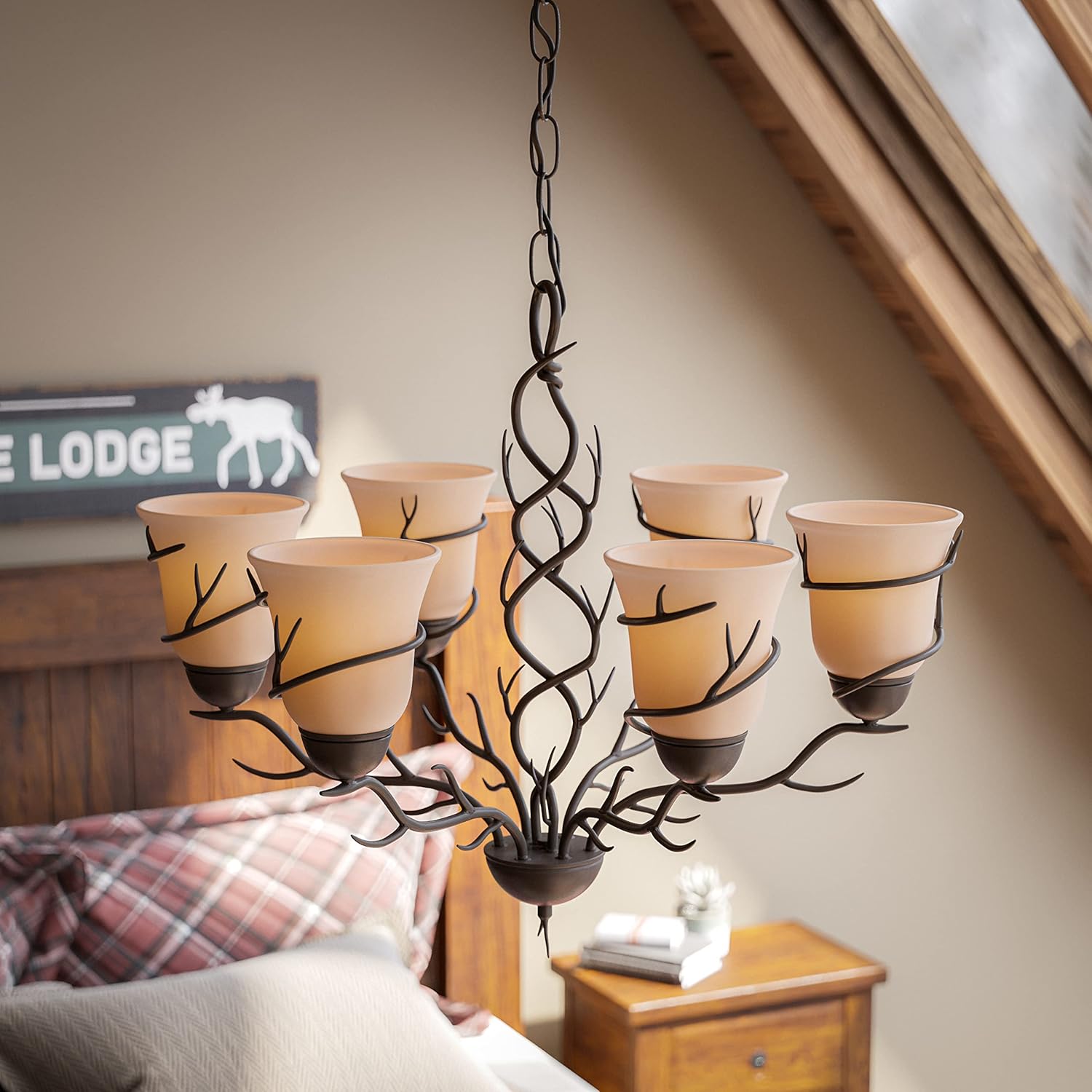 Close-up of the Kenroy Home Rustic 6 Light Chandelier's amber glass shades and branch-like metalwork