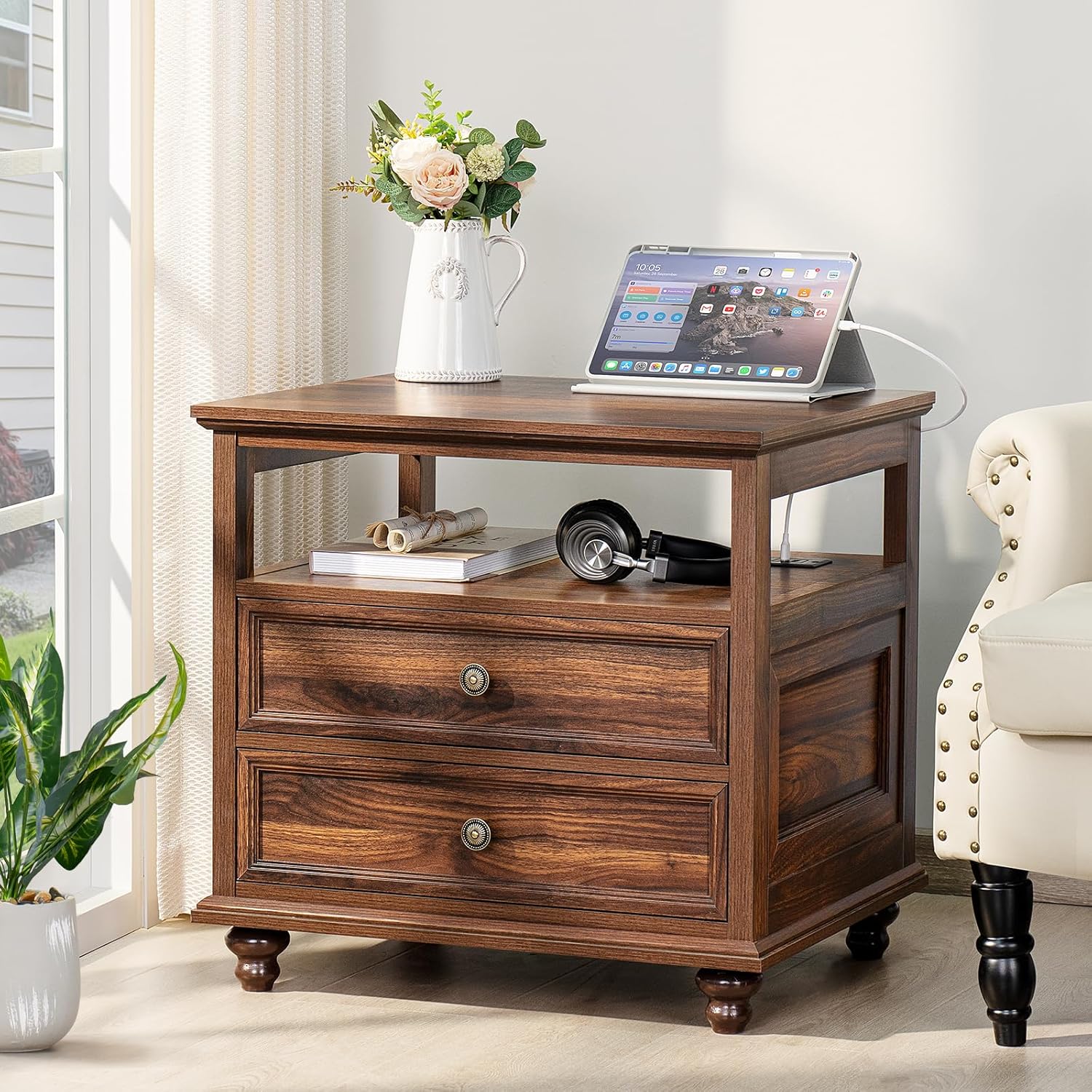 A brown wooden nightstand with a tablet charging on its top surface, showing the integrated charging station in use.