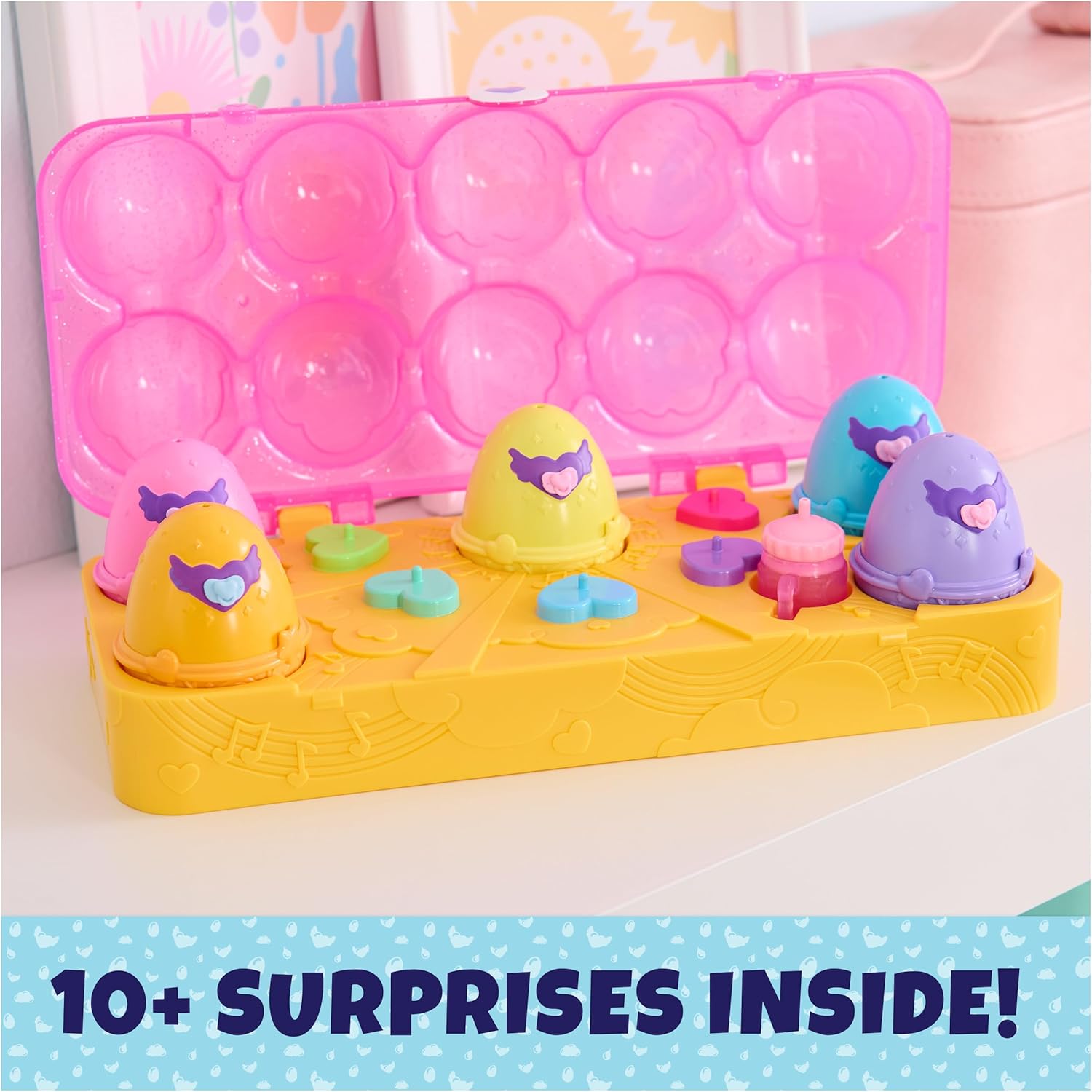 An open pink and yellow egg carton playset with several hatched Hatchimals figures and small accessories.