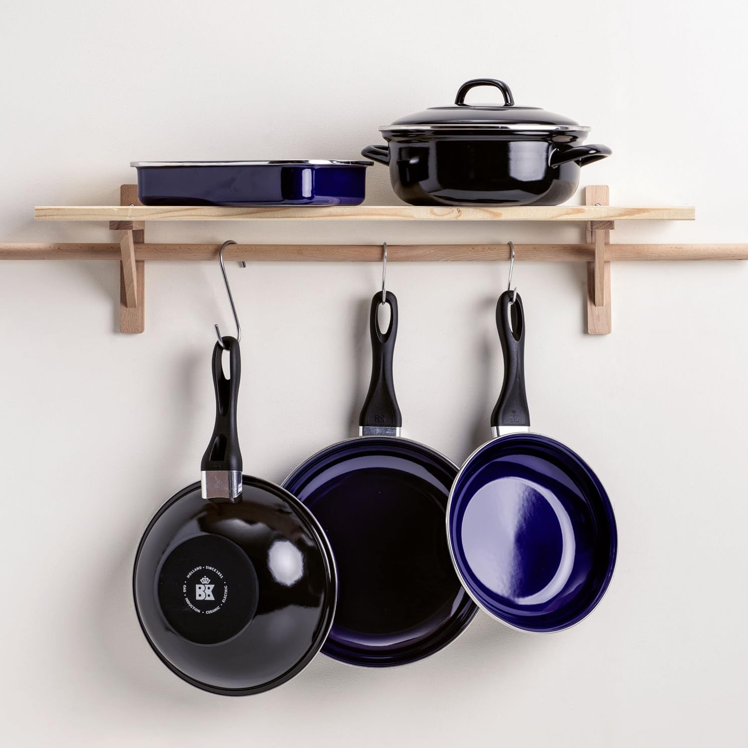 Multiple BK Fortalit pans and pots hanging on a kitchen rack and placed on a shelf.