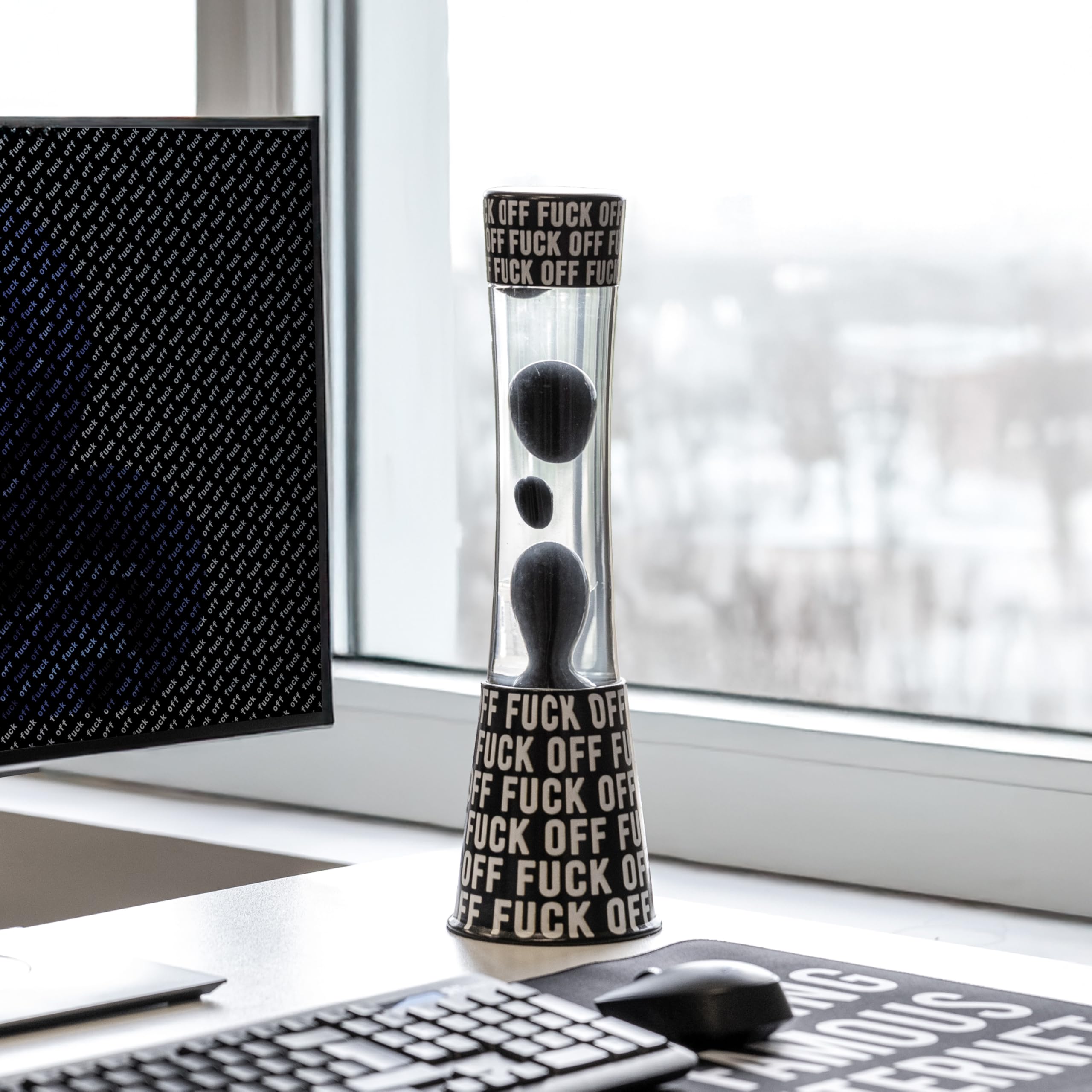 Fisura - Lampa lawa "f*ck off". Czarna podstawa z napisem, przezroczysty płyn i czarna lawa. Relaksujący efekt. Z zapasową żarówką. 11 cm x 11 cm x 39,5 cm.