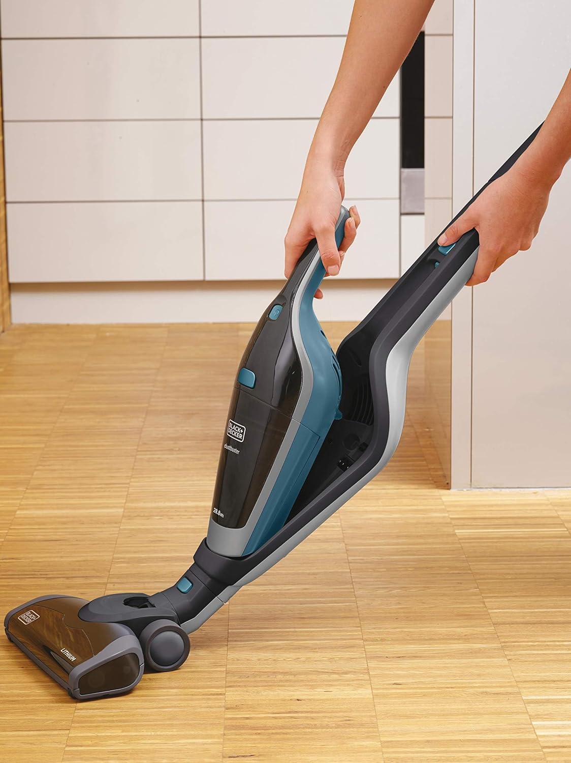 User detaching handheld vacuum from stick unit